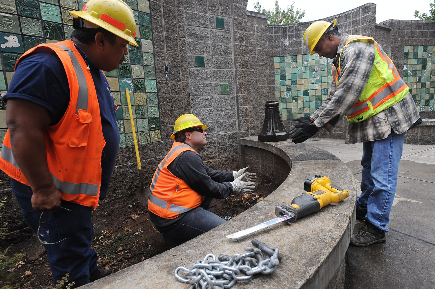 City of Vancouver workers Tony Castro, from left, Tracy Livingston and Kevin Battan prepare to install a motion-sensor light next to the Mill Plain Boulevard sound wall Friday to deter illegal activities in the alcoves.