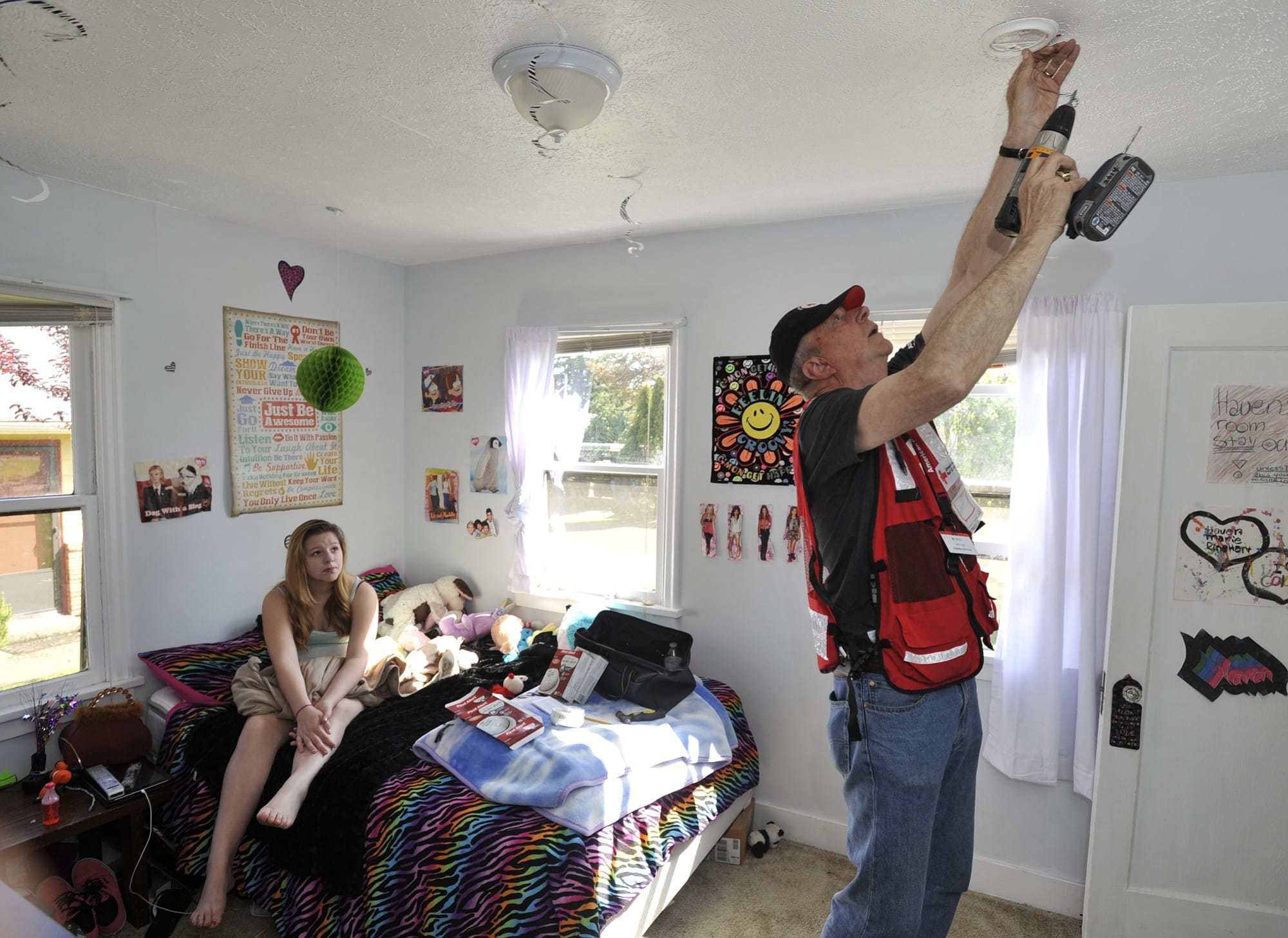Red Cross volunteer Jeff Kuter installs a smoke alarm in Haven Reinhart's room Saturday.