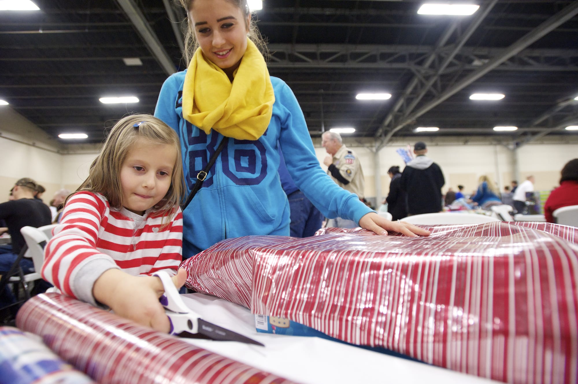 Alina Kiselev, 6, and her aunt Olya Bogush wrap a toy during the Santa's Posse gift wrapping night at the Clark County Event Center.