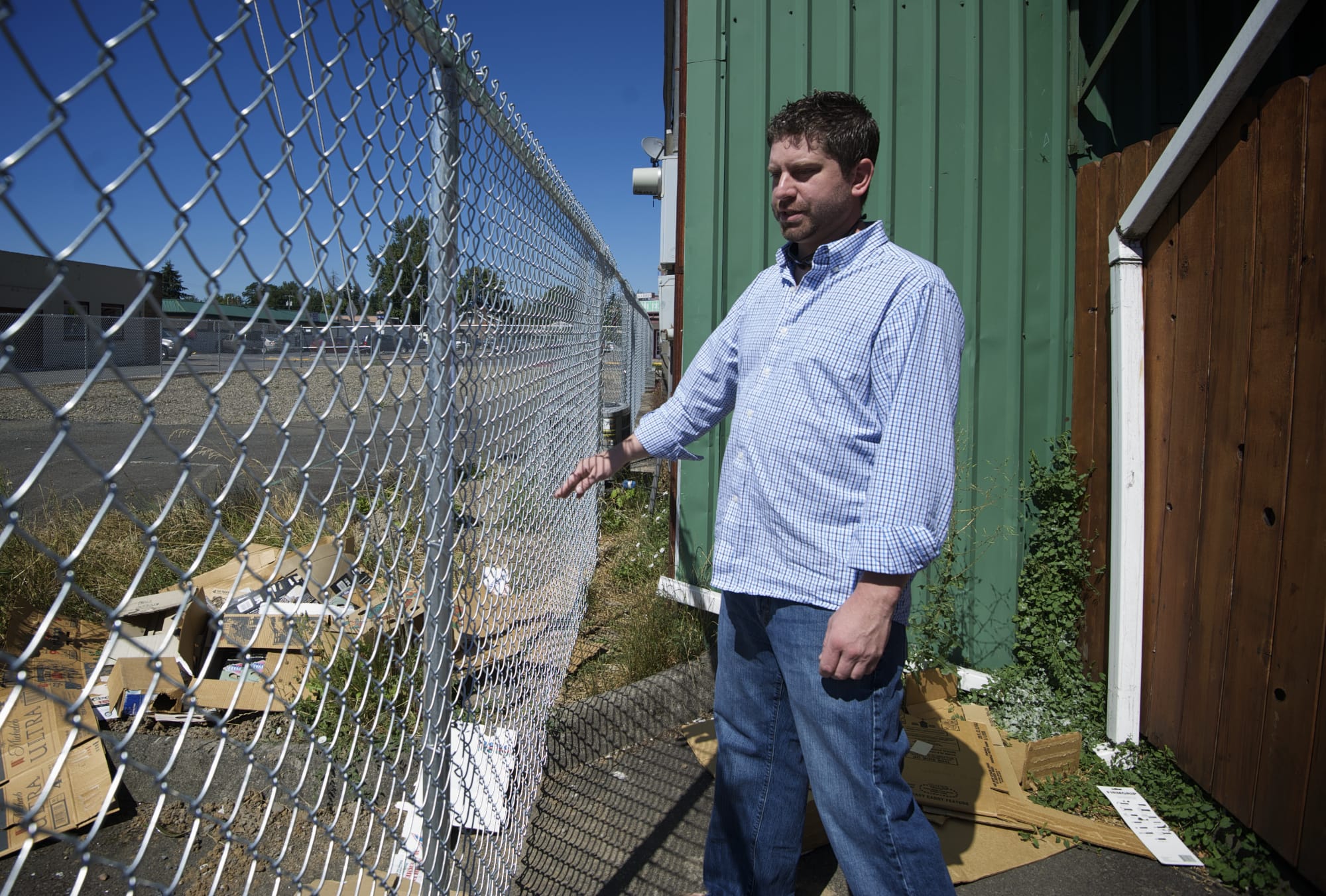 Andrew Tuttle, owner of Main Street Bar in Battle Ground, on Monday shows the tight clearance between the side of his business and a city fence.