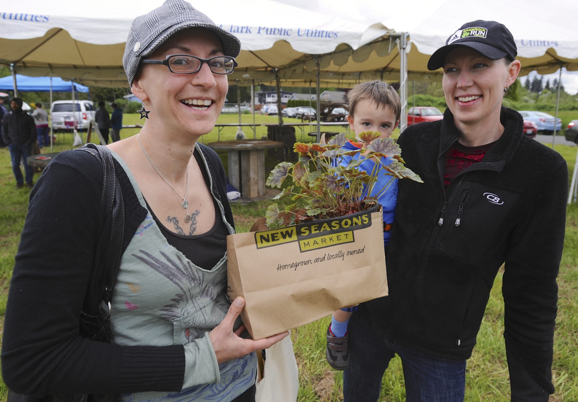 Wendy Galliart, left, and Molly Heikkinen, holding Louie, check out the plants at May 3 event to kick off a public market in Hazel Dell.