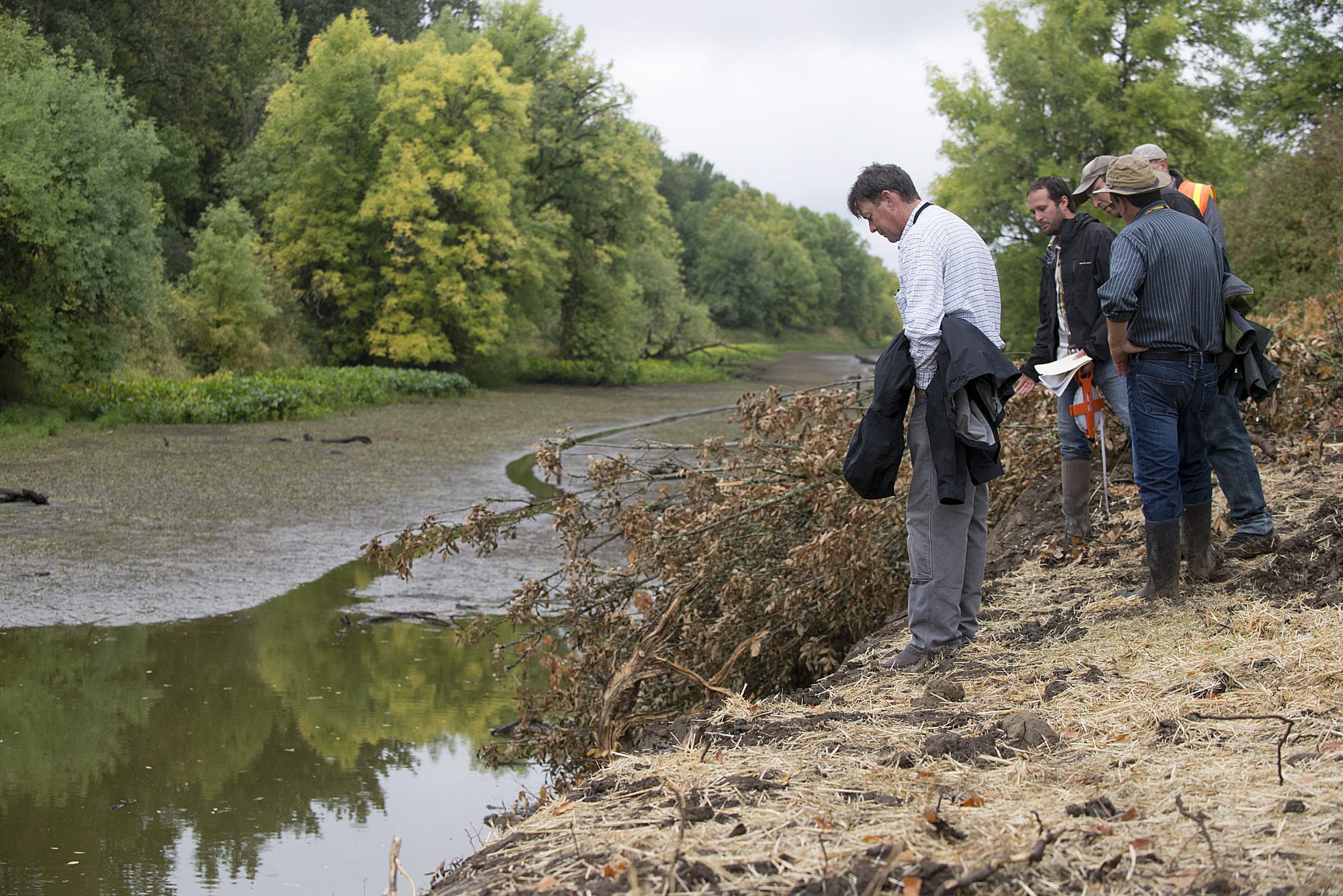 John Tyler of the Bonneville Power Administration, left, checks out the Buckmire Slough at the northern most barrier while joined by Tom Josephson of Columbia River Estuary Study Taskforce, second from left, on Friday.(Amanda Cowan/The Columbian )