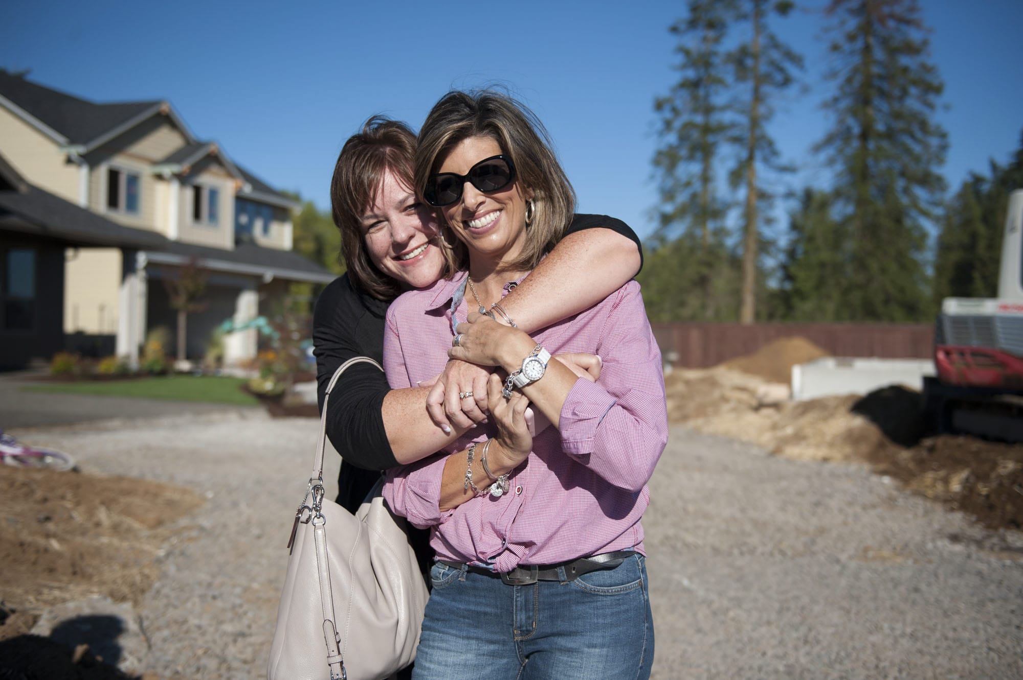 Tiffany Johnson, left, embraces her longtime friend Shelly Johnson at the site of Shelly and her husband, Craig’s, new home. Tiffany Johnson created a nonprofit group, Raise the Roof Foundation, to raise money to build the Johnsons a new home.