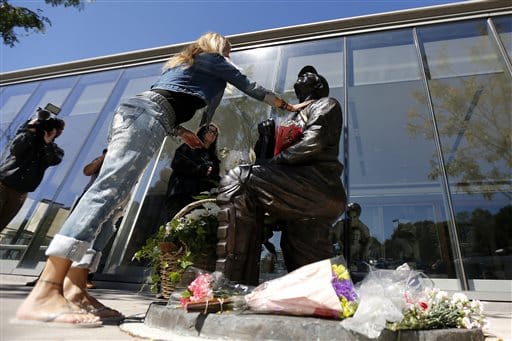 Michele Bartelloni, of Fairfield, N.J., touches a statue of former New York Yankees hall of fame catcher Yogi Berra after placing flowers outside of the Yogi Berra Museum, Wednesday, Sept. 23, 2015, in Little Falls, N.J. Berra, who played in more World Series games than any other major leaguer, and was a three-time American League Most Valuable Player, died Tuesday, Sept. 22, 2015, of natural causes at his home in New Jersey, according to Dave Kaplan, the director of the Yogi Berra Museum.  He was 90.