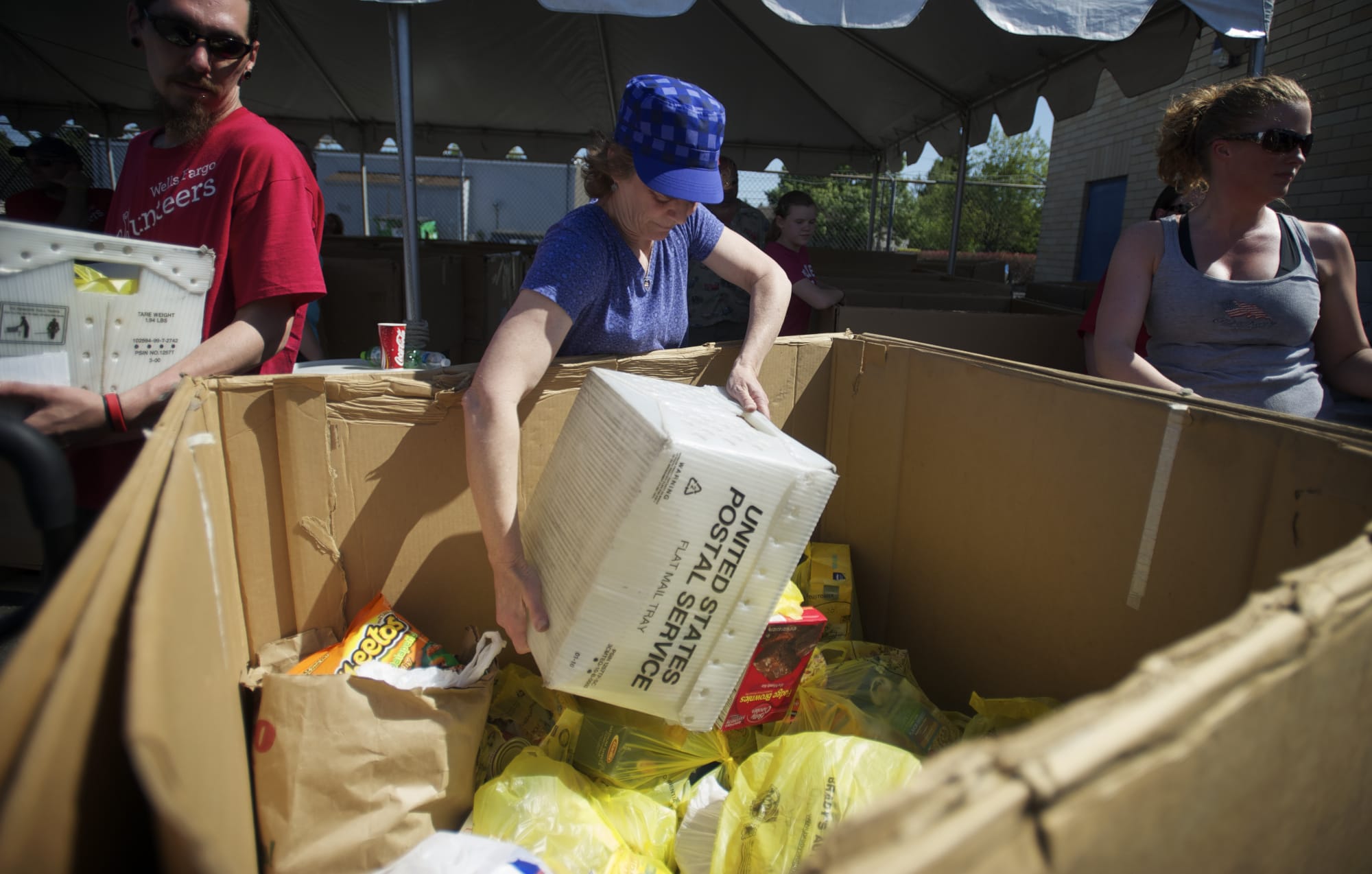 Volunteer Laura Fernandez helps unload canned goods from mail crates at the Caples Road post office during the 2012 letter carriers food drive.
