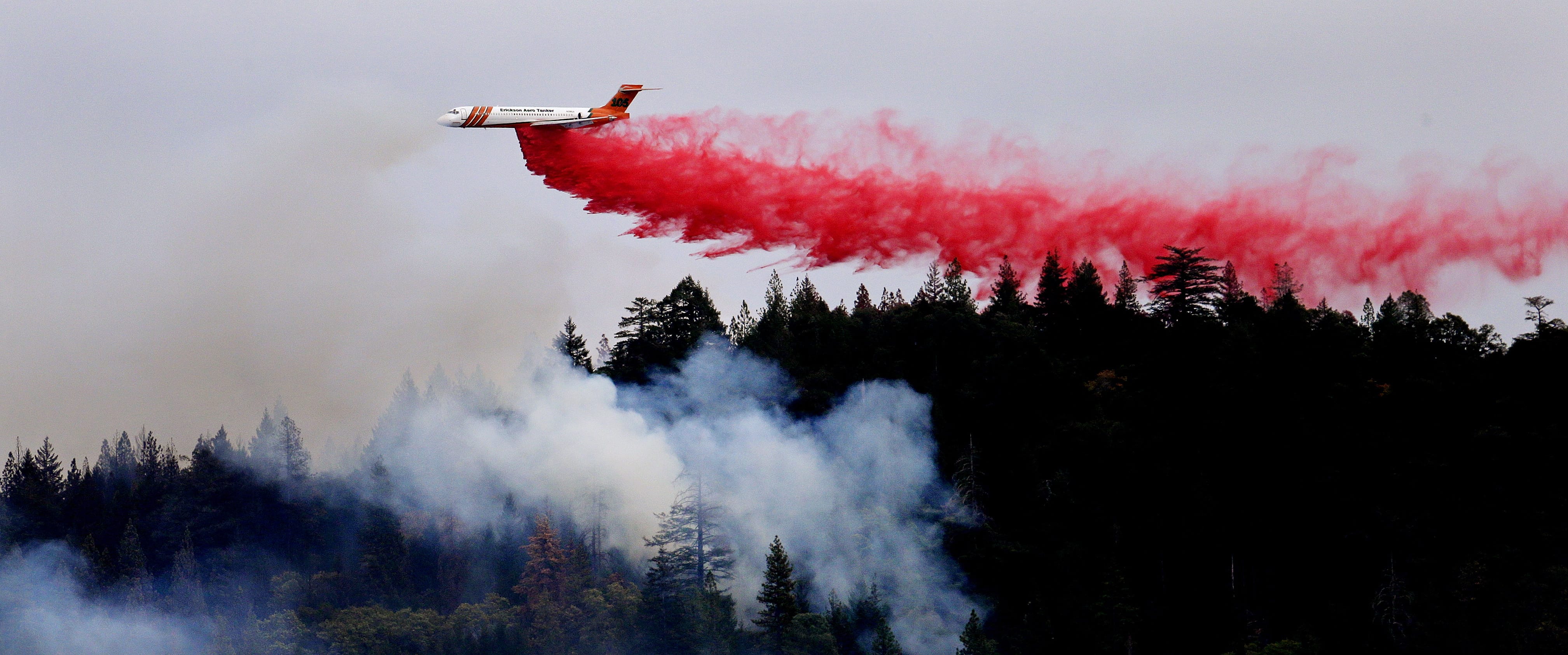A firefighting plane drops a load of fire retardant over a smoldering hillside Tuesday in Middletown, Calif. The fire that sped through Middletown and other parts of rural Lake County, less than 100 miles north of San Francisco, has continued to burn since Saturday despite a massive firefighting effort.