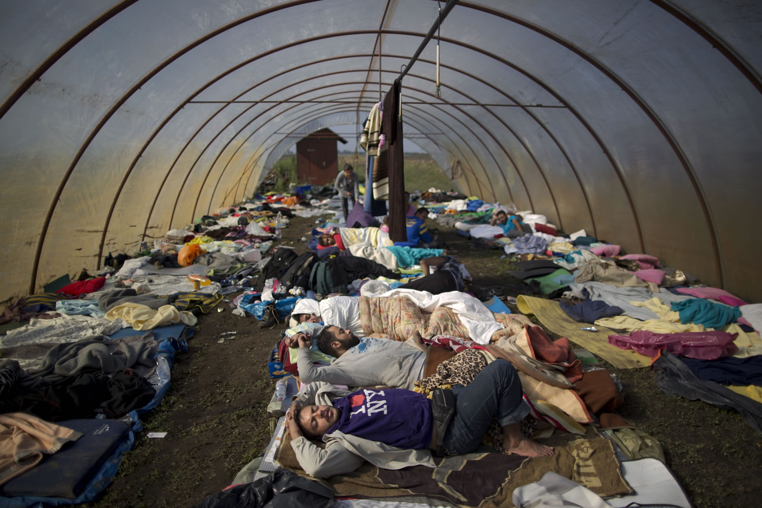 Syrian people sleep inside a greenhouse at a makeshift camp for asylum seekers near Roszke, southern Hungary, Sunday, Sept. 13, 2015. Hundreds of thousands of Syrian refugees and others are still making their way slowly across Europe, seeking shelter where they can, taking a bus or a train where one is available, walking where it isn't.