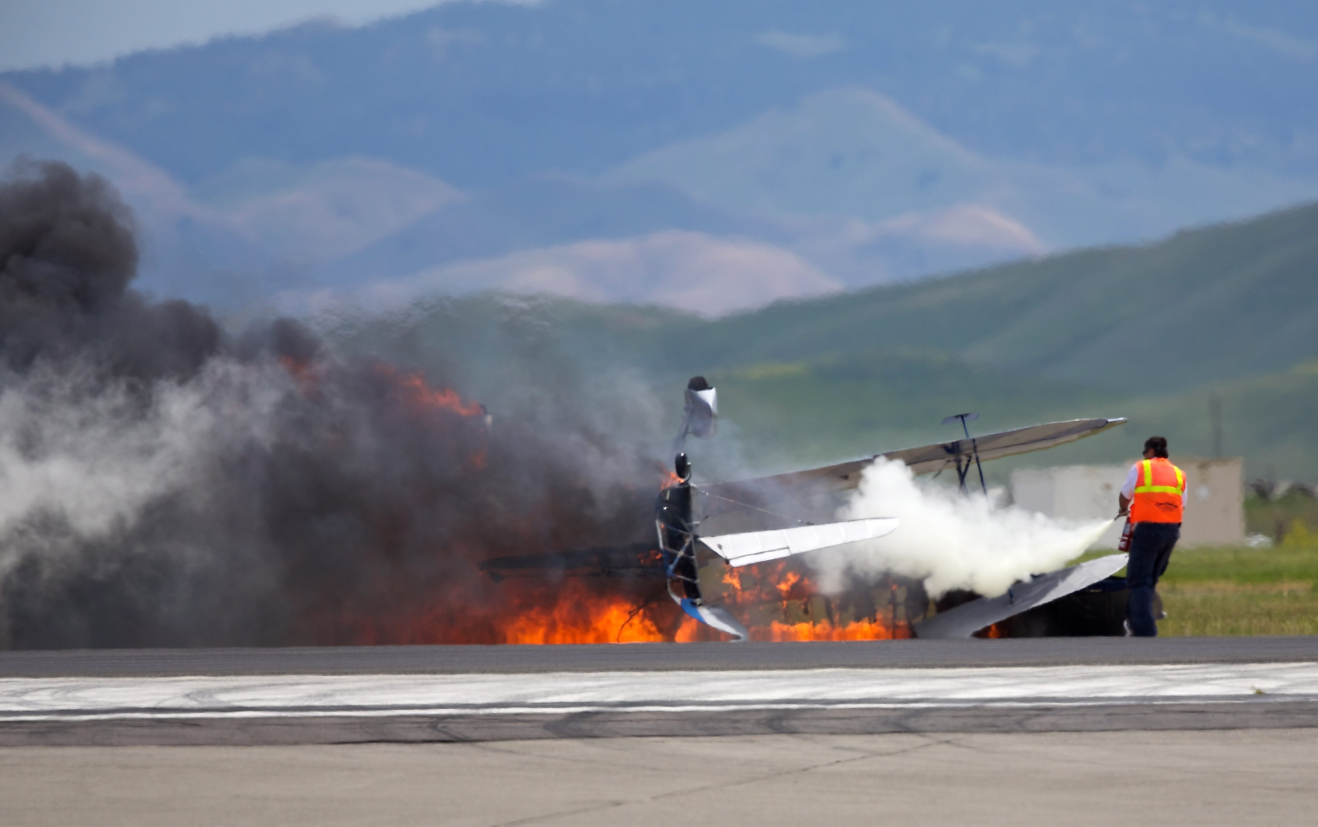 A worker fights a fire after a vintage biplane crashed upside-down on a runway at an air show at Travis Air Force Base in Fairfield, Calif., on Sunday.