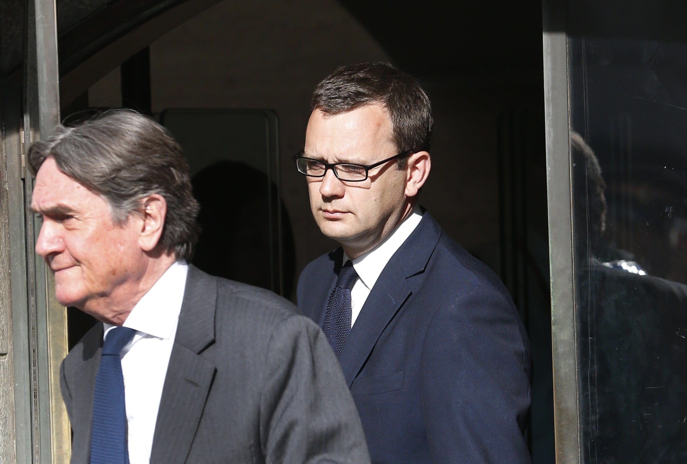 Andy Coulson, background, former News of the World editor leaves the Central Criminal Court in London on Tuesday.