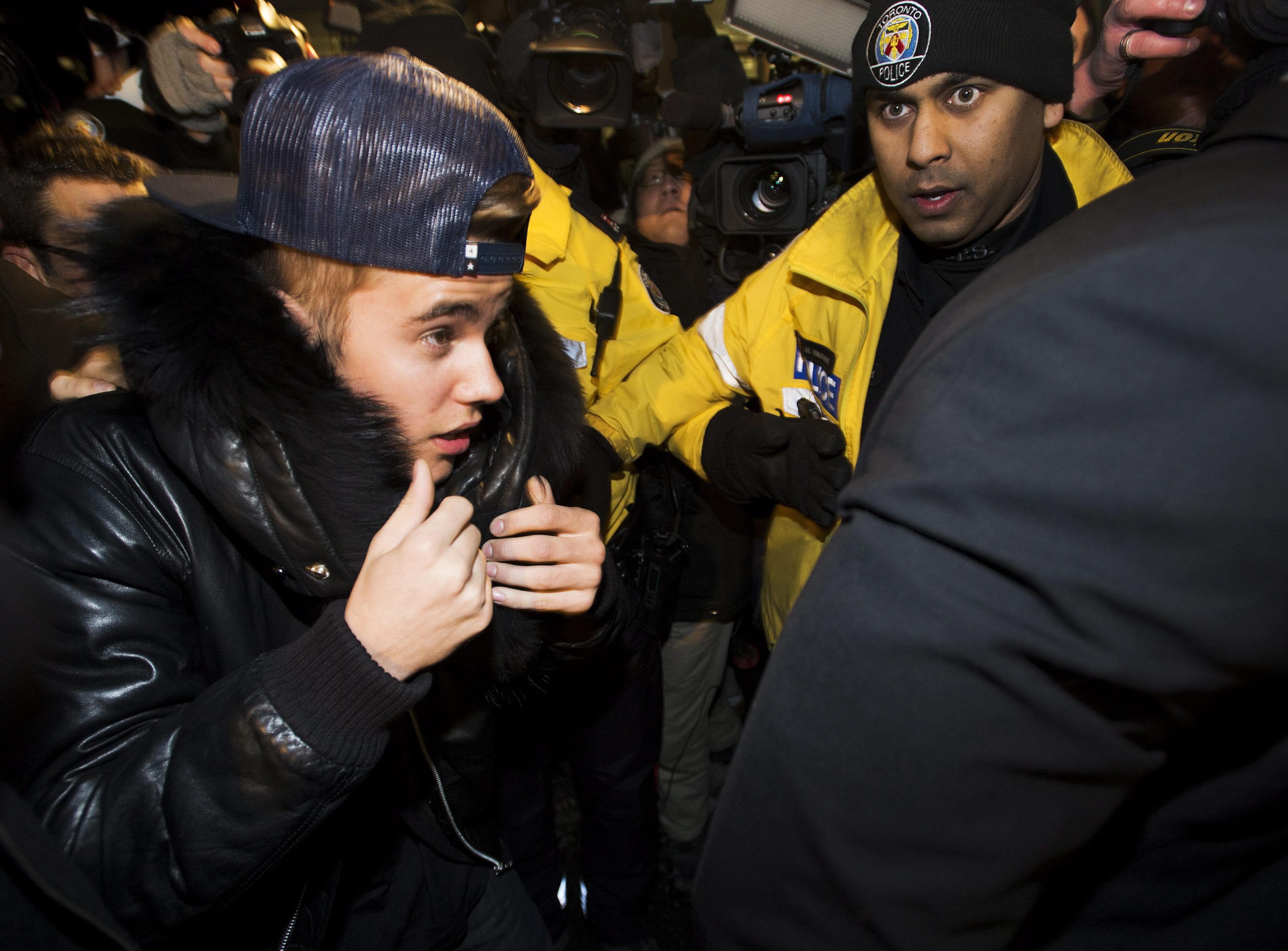 Canadian musician Justin Bieber is swarmed by media and police officers Wednesday as he turns himself in to city police for an expected assault charge, in Toronto.