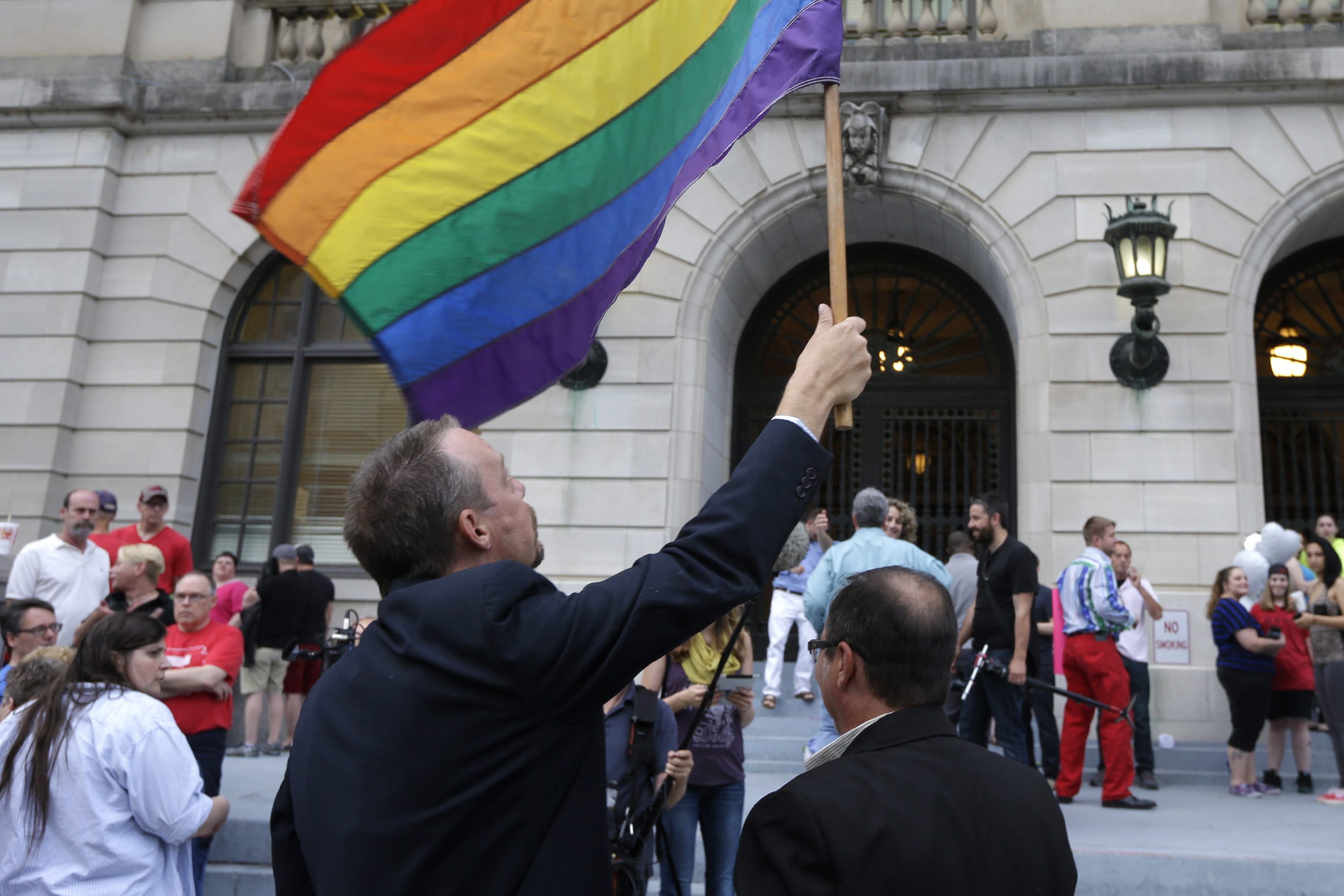 Same-sex marriage supporter Shon DeAmon holds a flag as his partner James Porter, right, watches at the Pulaski County Courthouse in Little Rock, Ark., on Monday.