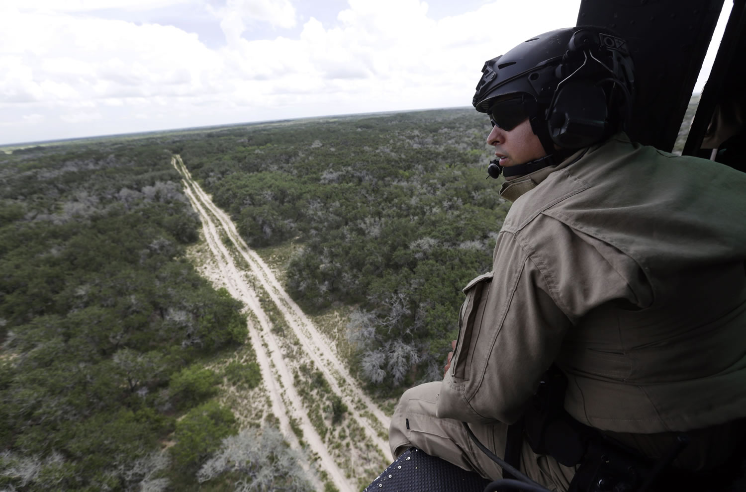 Eric Gay/Associated Press
A U.S. Customs and Border Protection Air and Marine agent peers out of a helicopter during a patrol flight near the Texas-Mexico border near McAllen, Texas. The Border Patrol has been joined by many official and unofficial guards.  Since illegal immigration spiked in the Rio Grande Valley this summer, the Border Patrol has dispatched more agents, the Texas Department of Public Safety has sent more troopers and Texas Gov. Rick Perry deployed as many as 1,000 guardsmen to the area.