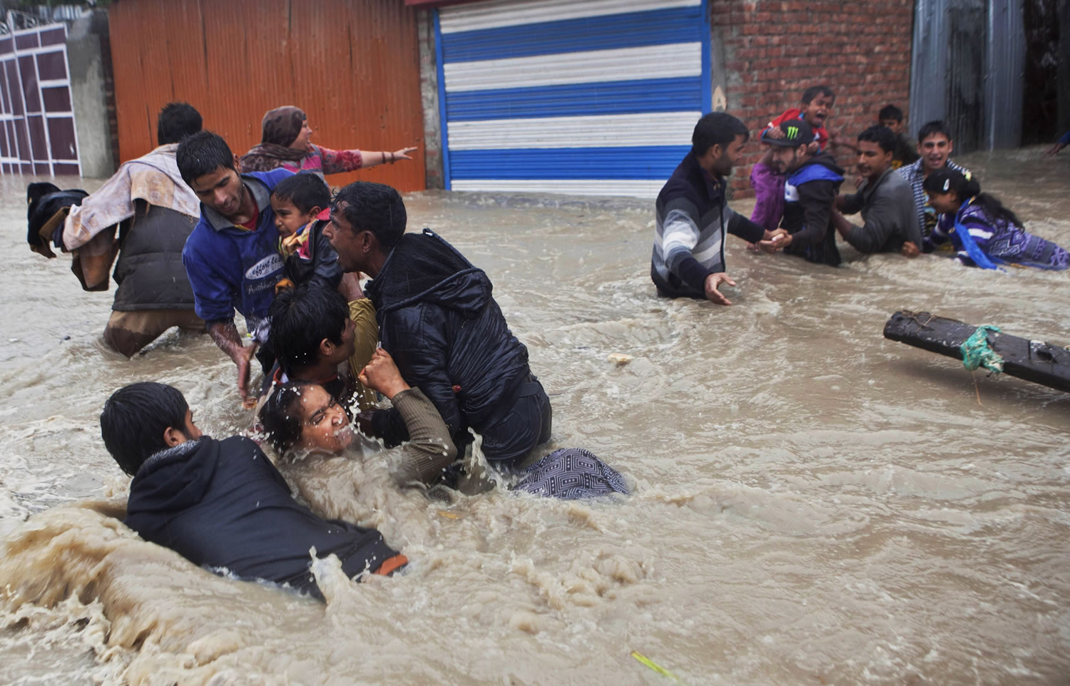 People struggle against strong currents in floodwaters while trying to move to safer ground Thursday in Srinagar, India.