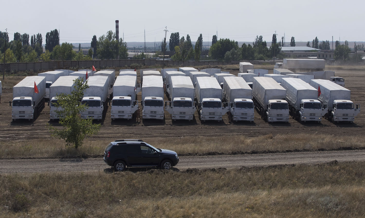 White trucks that Russia says contain humanitarian aid are parked in a field Thursday in Russia about 18 miles from Ukraine border.