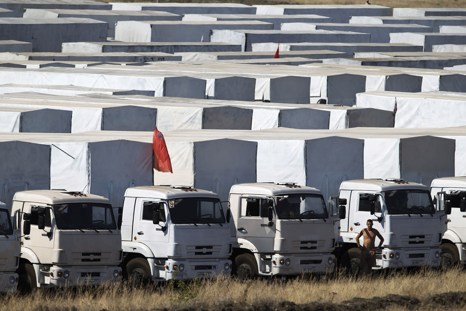 A driver stands near trucks forming part of an aid convoy parked in a field Saturday about 17 miles from the Ukrainian border, near Kamensk-Shakhtinsky, Rostov-on-Don region, Russia.