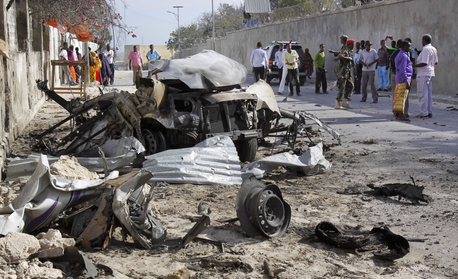Somalis gather Friday near the wreckage of one of the vehicles used for a car bomb, following a militant attack on the presidential palace in Mogadishu, Somalia.
