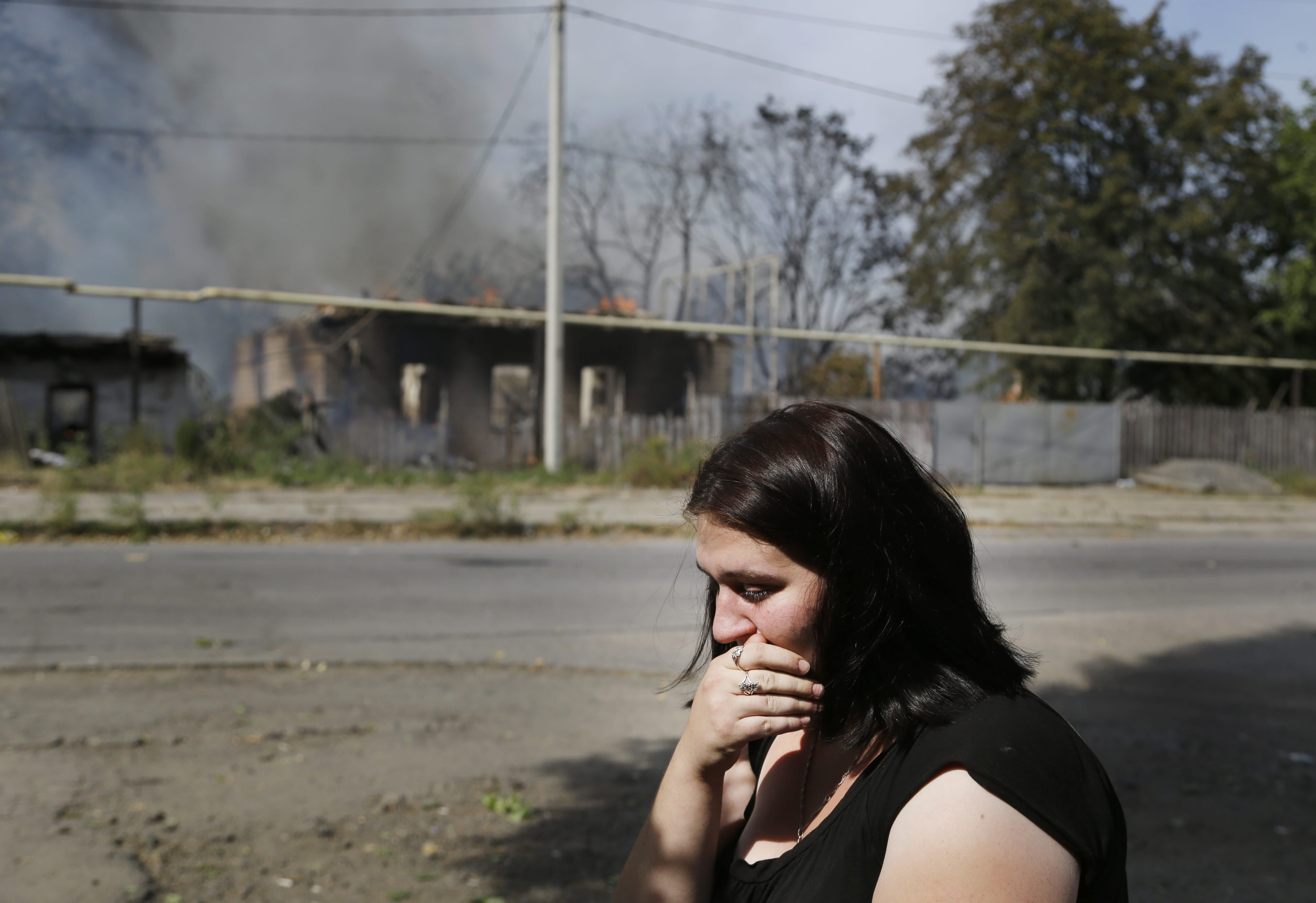 A local woman cries Sunday in front of her burning house after shelling in Donetsk, Ukraine.