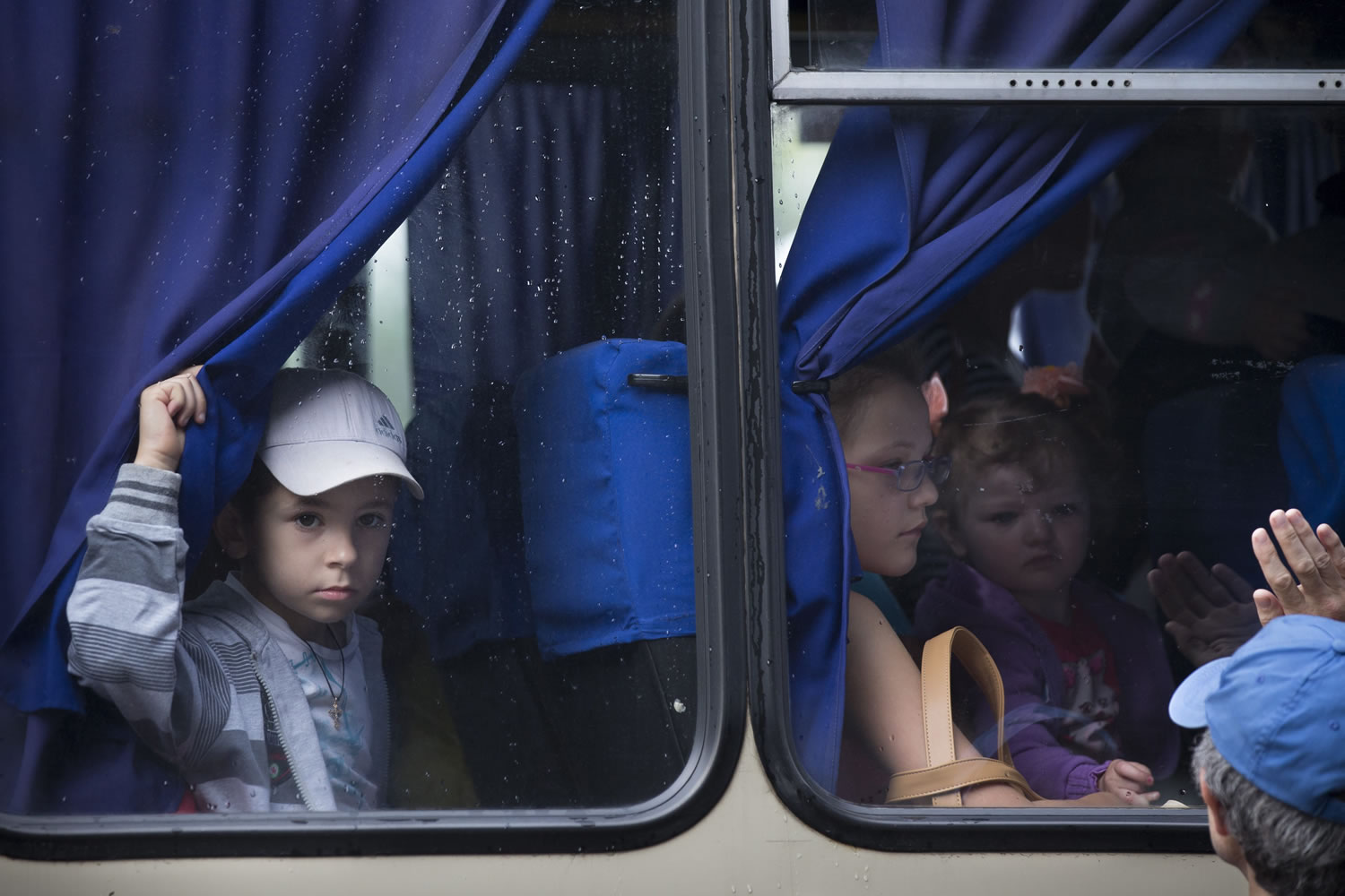 Children look through the bus window while leaving the city fearing the shelling attacks during fighting between Ukrainian government forces and pro-Russian militants in Slovyansk, Ukraine, Thursday, May 29, 2014.  In Slovyansk, a city 90 kilometers (55 miles) north of Donetsk there have been repeated clashes over the past few weeks, with residential areas being shelled by mortars Wednesday from government forces.