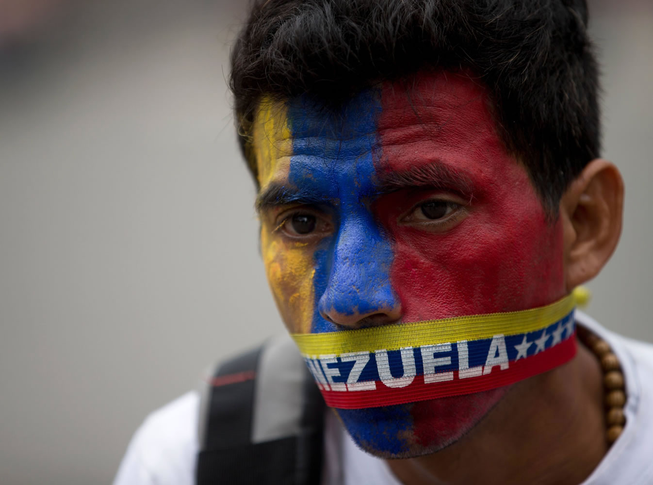 A man wears a narrow strip featuring the colors of Venezuela's flag over his mouth in protest Thursday of officials breaking up camps in Caracas, Venezuela, maintained by student protesters.