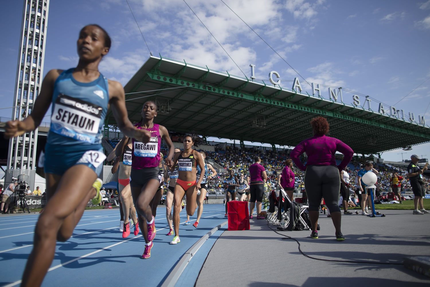 Competitors pass the shot-put area during the women's 1500 meters during the IAAF Diamond League Grand Prix competition on Randall's Island, Saturday in New York.