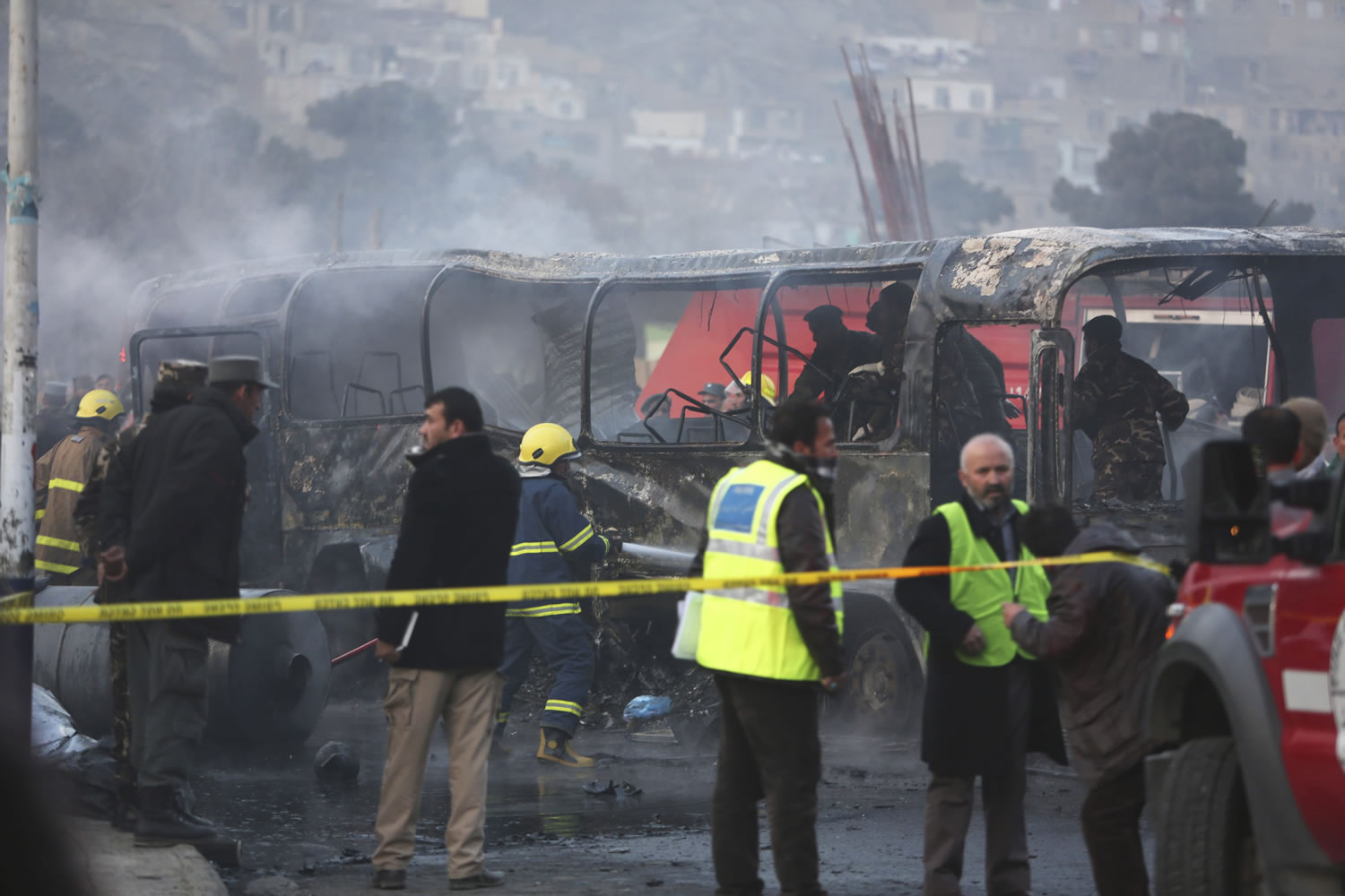 Afghan security guards inspect a damaged bus at the site of a suicide attack Saturday in Kabul, Afghanistan.