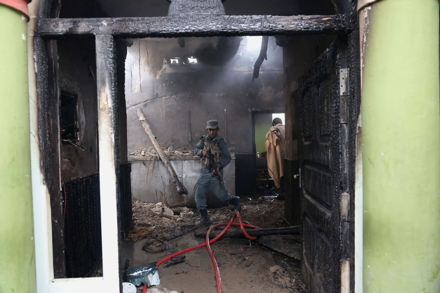 An Afghan police officer walks around inside the nearby state-run Afghan radio and television building badly damaged when a suicide car bomber blew up his vehicle near a police station in Jalalabad, Afghanistan, on Thursday.