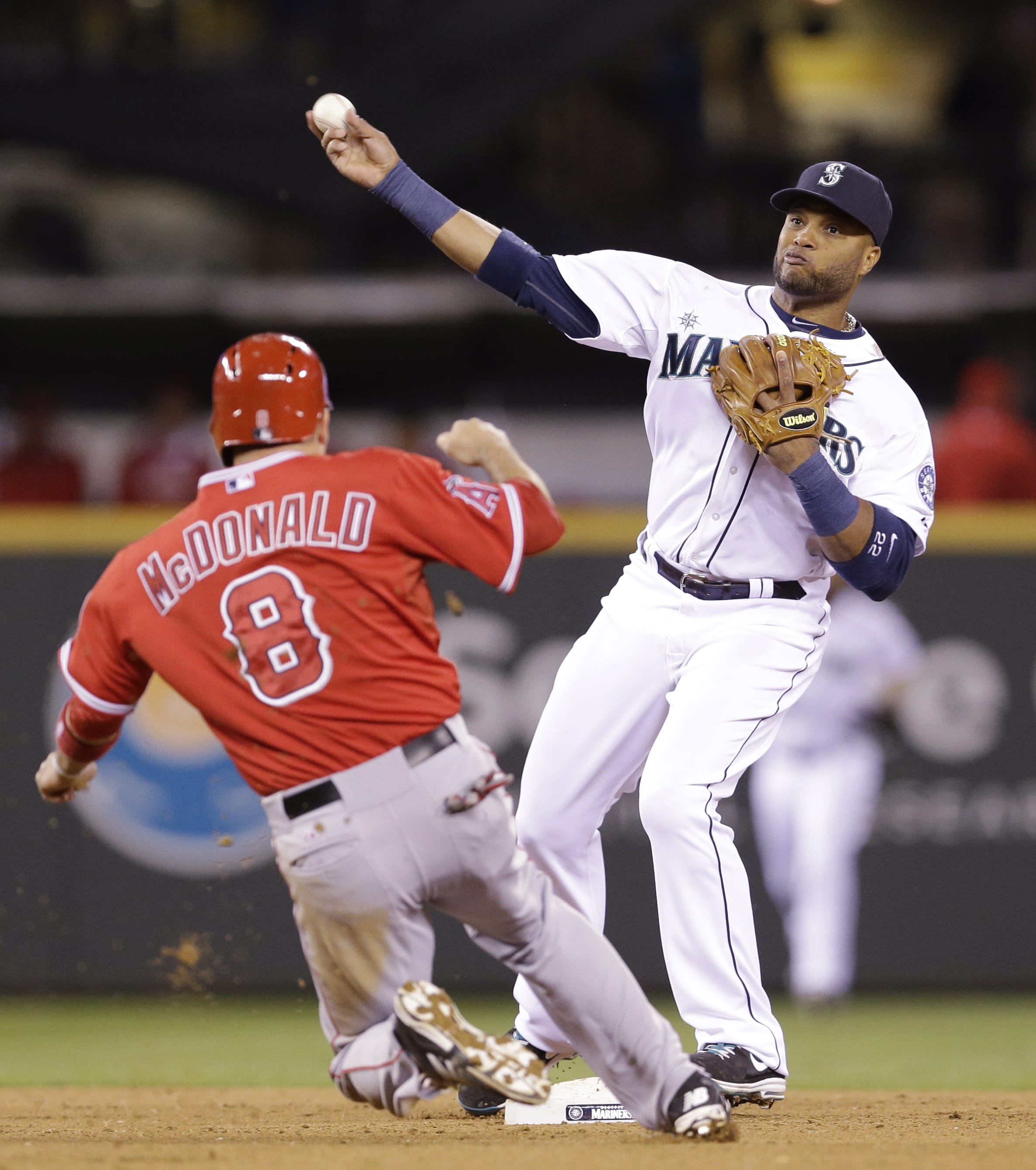 Seattle Mariners second baseman Robinson Cano, right, throws to first after forcing out Los Angeles Angels' John McDonald at second base in the fifth inning of a baseball game Wednesday, April 9, 2014, in Seattle. Mike Trout was safe at first.