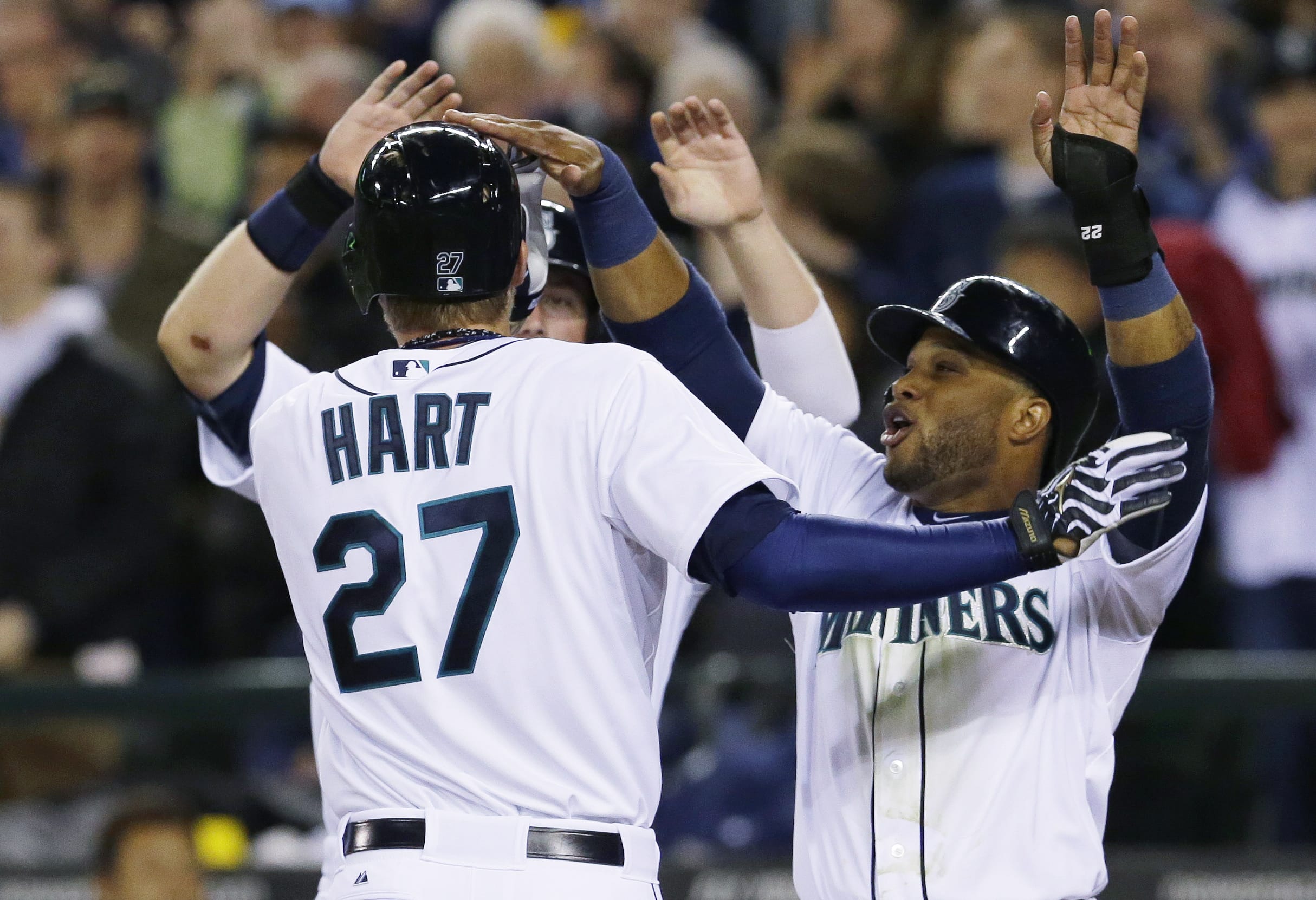 Seattle's Corey Hart (27) is greeted at the plate by Robinson Cano, right, and Justin Smoak after Hart's three-run home run.