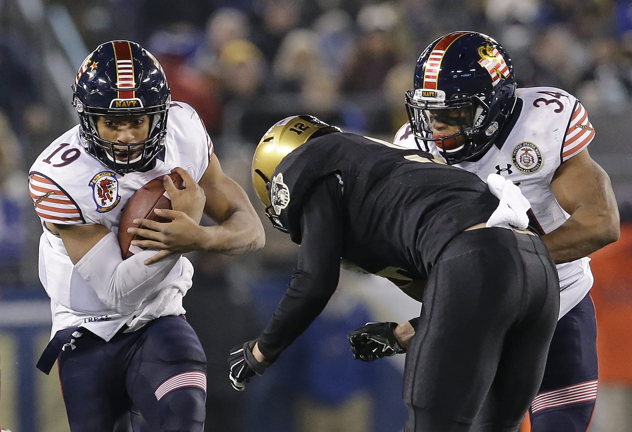 Navy quarterback Keenan Reynolds, left, dodges Army defensive back Hayden Pierce as he rushes the ball past teammate Noah Copeland in the second half Saturday, Dec. 13, 2014, in Baltimore. Navy won 17-10.