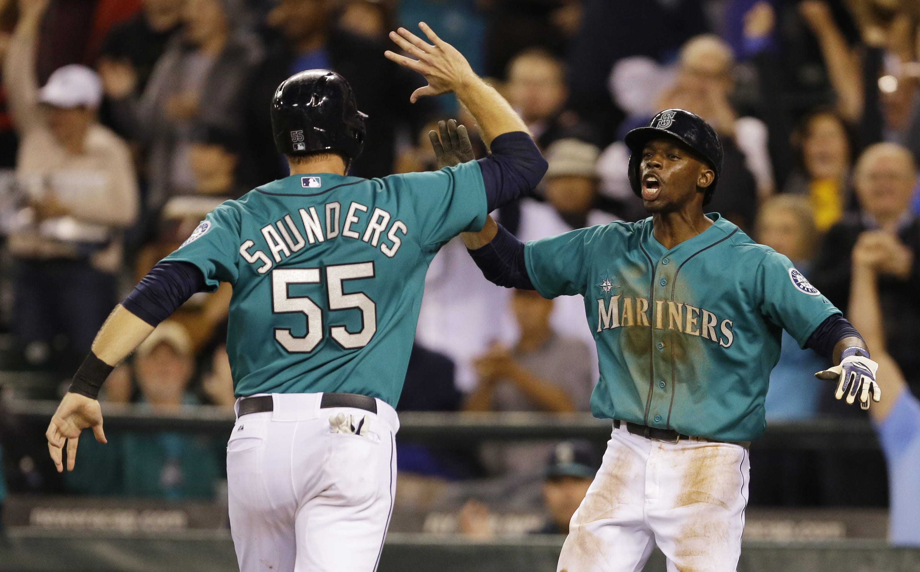 Seattle Mariners' James Jones, right, greets Michael Saunders at the plate after they both scored on a triple hit by Mariners' Brad Miller in the eighth inning of a baseball game against the Houston Astros, Monday, Sept. 8, 2014, in Seattle. (AP Photo/Ted S.