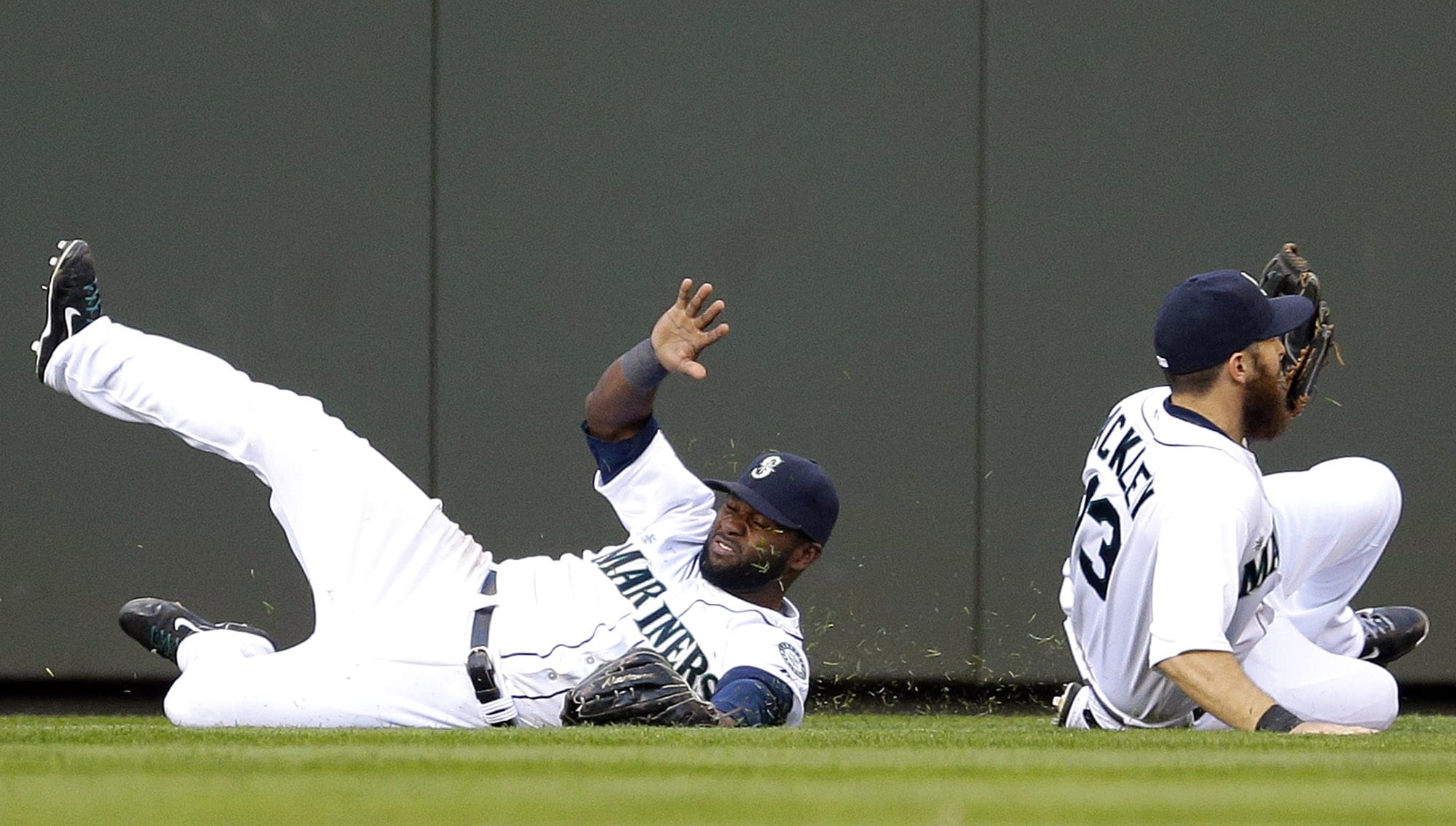 Seattle Mariners center fielder Abraham Almonte, left, slides in the outfield grass past center fielder Dustin Ackley, right, who caught but then dropped a fly ball hit by Oakland Athletics' Brandon Moss in the third inning of a baseball game on Saturday, April 12, 2014, in Seattle. (AP Photo/Ted S.