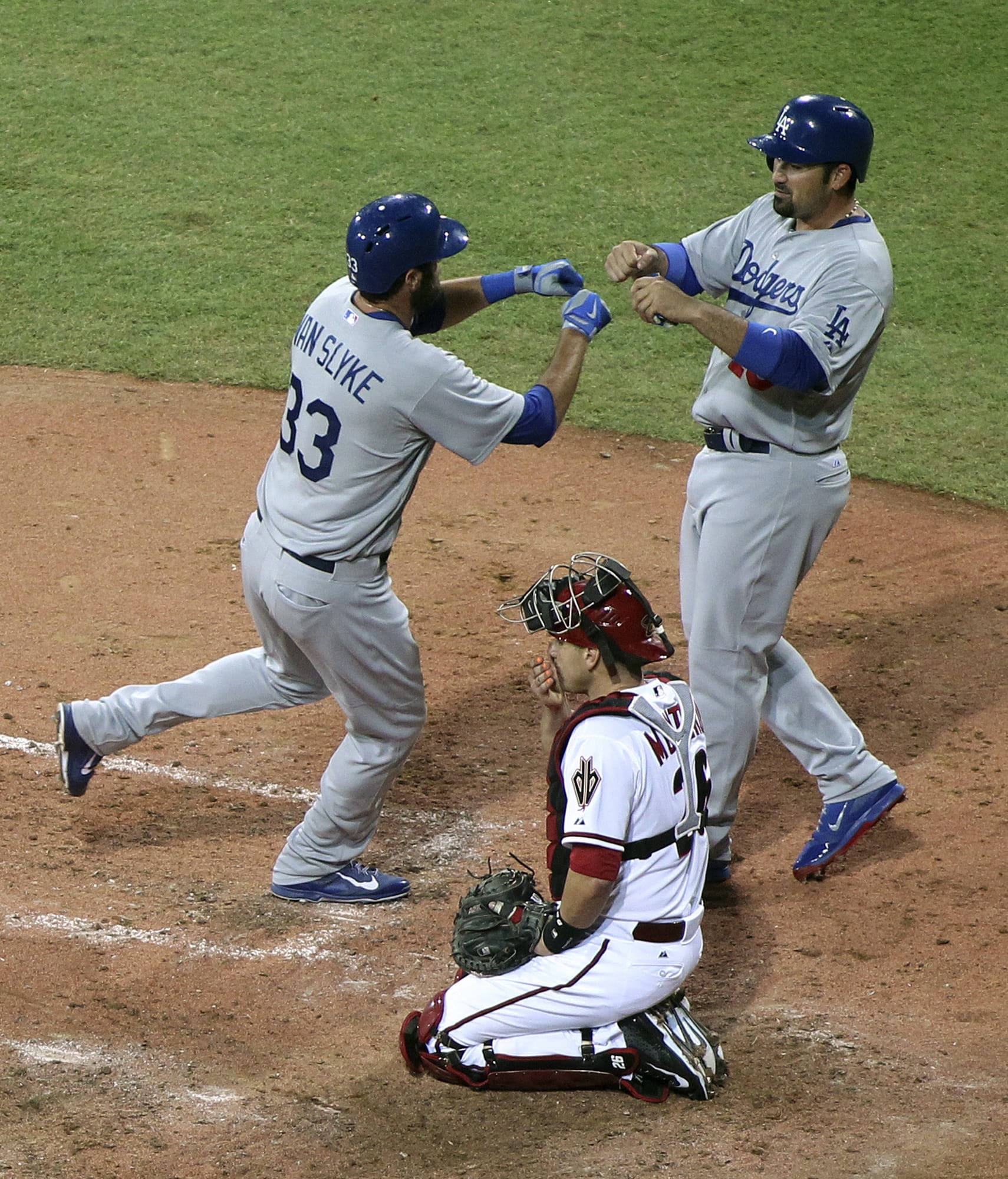 Diamondbacks' catcher Miguel Montero kneels as the Dodgers' Scott Van Slyke, left, is congratulated by teammate Adrian Gonzalez, right, after Van Slyke hit a two-run home run in the Major League Baseball opening game between the Los Angeles Dodgers and Arizona Diamondbacks at the Sydney Cricket Ground in Sydney, Australia Saturday, March 22, 2014.   The Dodgers won the game 3-1.