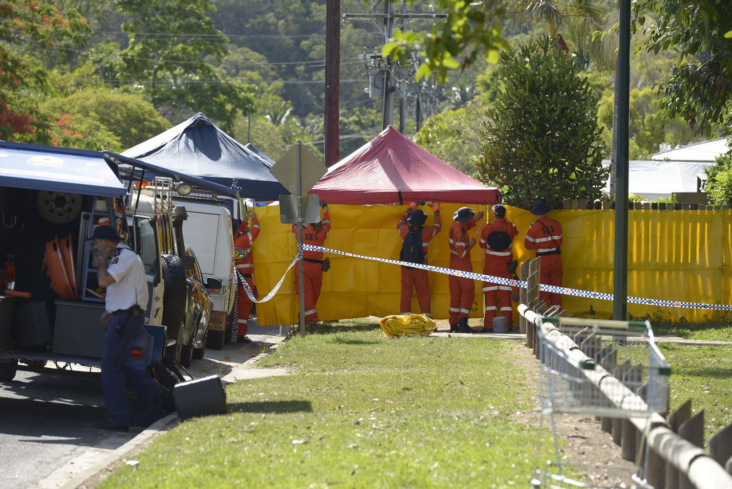 Emergency services workers cover off the perimeter fence of a house Friday where eight children were found dead in a Cairns suburb in far north Queensland, Australia.