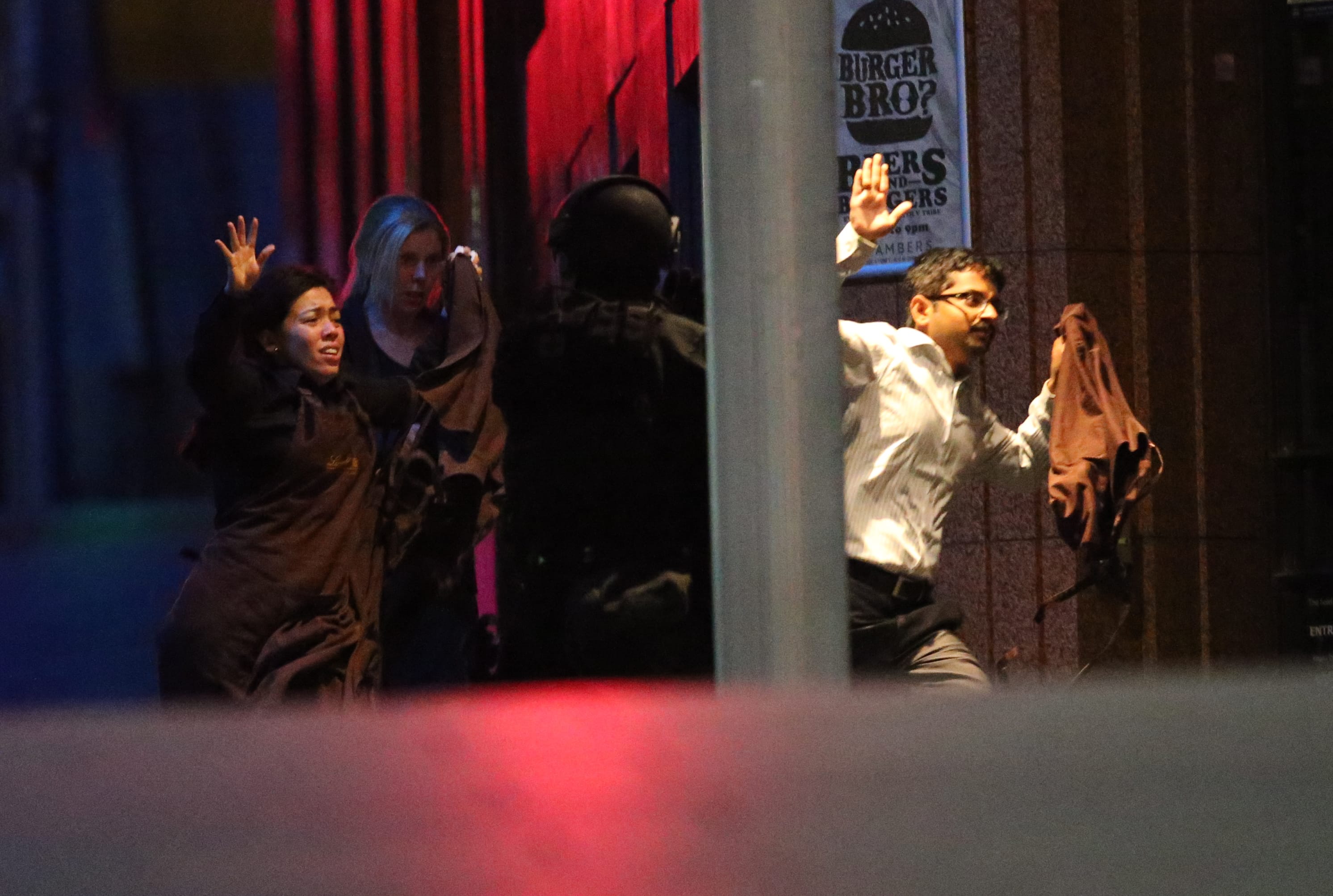 Hostages run towards armed tactical response police as they run to freedom from a cafe in Sydney early Tuesday.