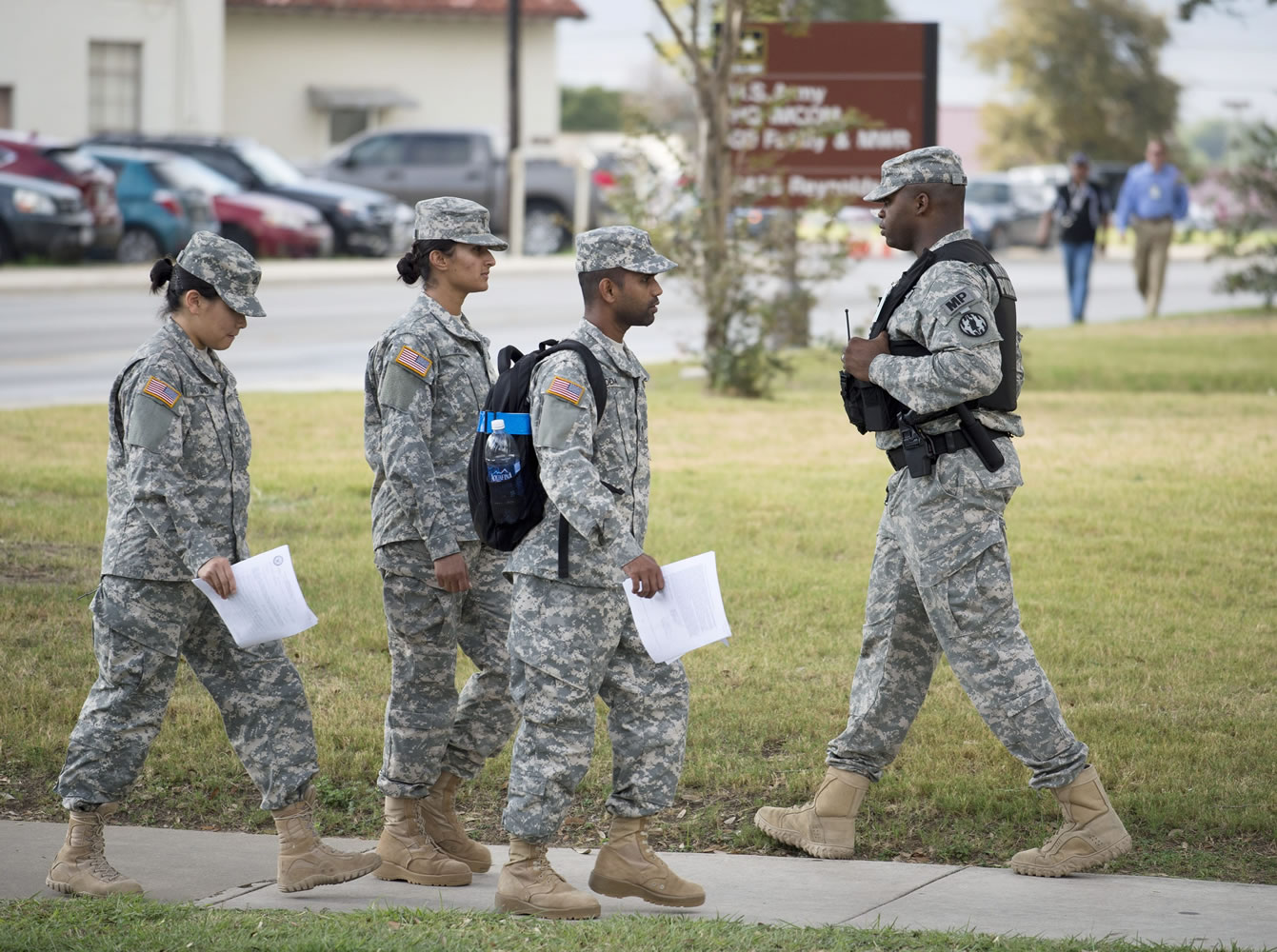 Soldiers walk past a military police officer, right, patrolling the perimeter of the US Army IMCOM HQ building prior to the Article 32 preliminary hearing to determine if Army Sgt. Bowe Bergdahl will be court martialed Thursday  at Fort Sam Houston in San Antonio. Bergdahl, who left his post in Afghanistan and was held by the Taliban for five years, is charged with desertion and misbehavior before the enemy.