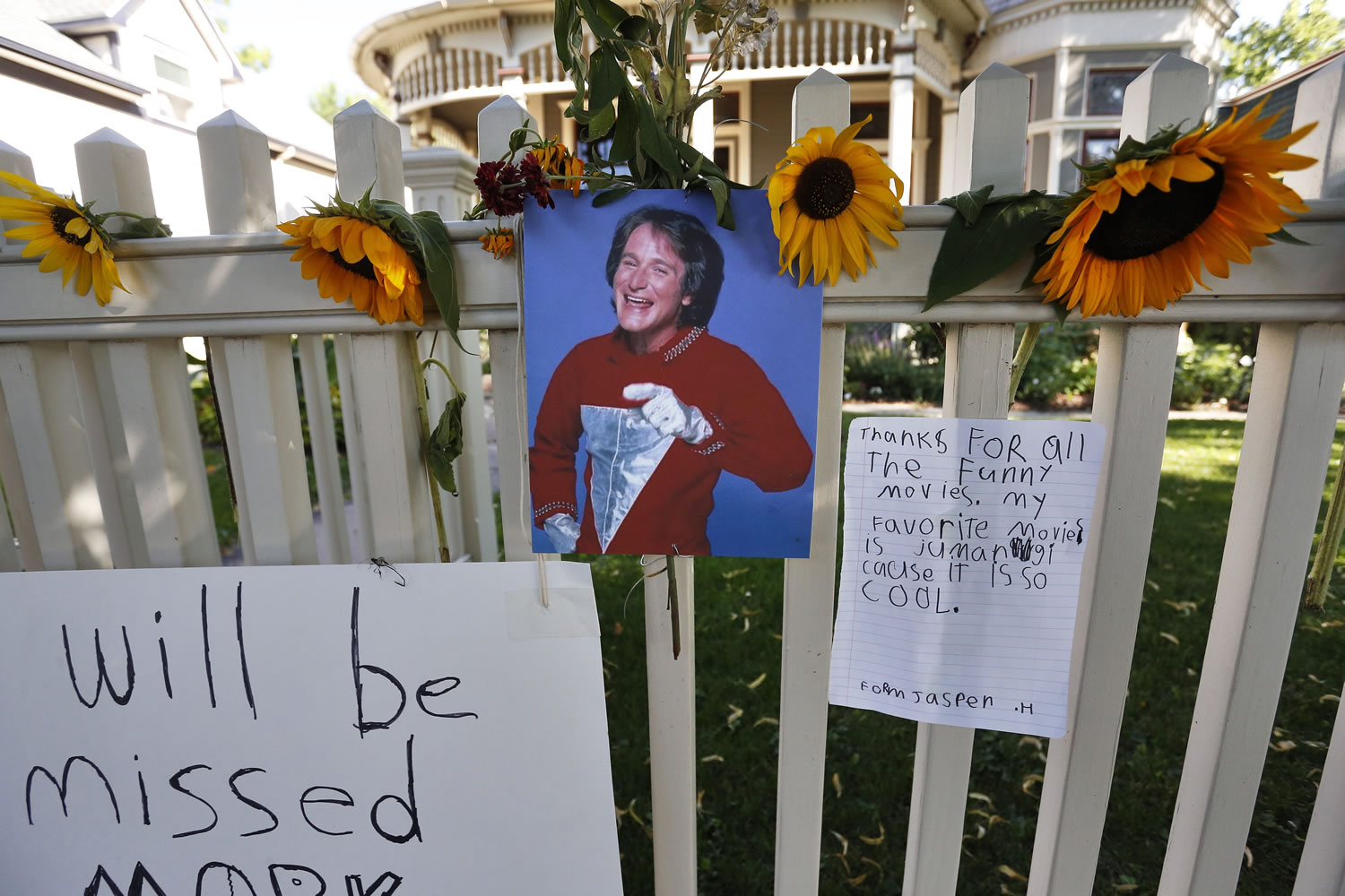 A photo of the late actor Robin Williams playing Mork from Ork hangs with flowers and notes left by people paying their respects at a makeshift  memorial in Boulder, Colo., on Tuesday, outside the home where the 80s TV series &quot;Mork &amp; Mindy,&quot; starring Williams, was set. Williams, the Academy Award winner and comic supernova whose explosions of pop culture riffs and impressions dazzled audiences for decades and made him a gleamy-eyed laureate for the Information Age, committed suicide Monday. He was 63.