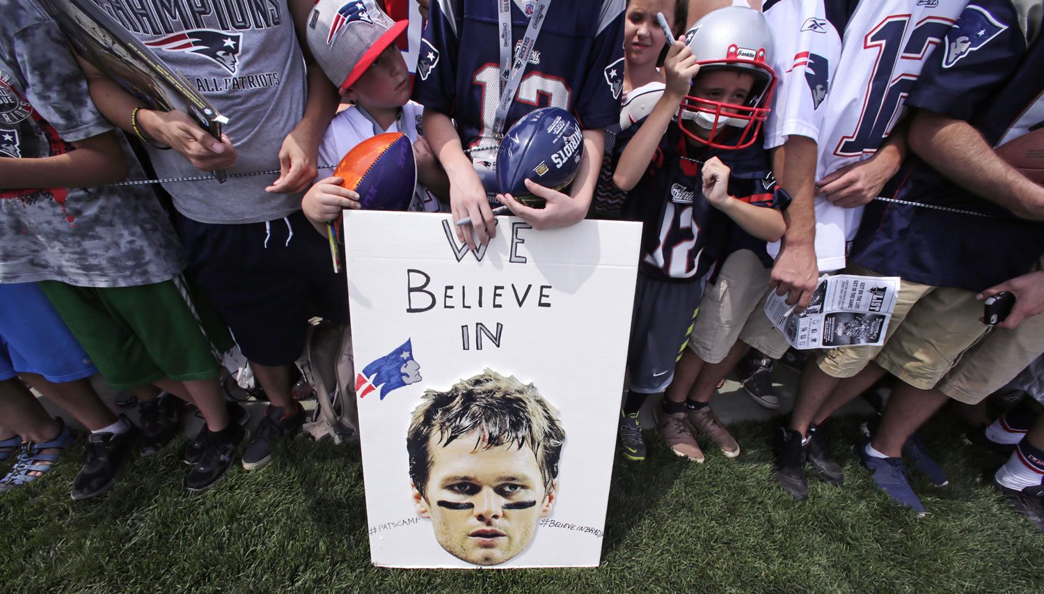 New England Patriots fans wait July 30 for practice to complete, while standing behind a sign supporting quarterback Tom Brady, during an NFL football training camp in Foxborough, Mass. A federal judge deflated "Deflategate" on  Thursday, erasing New England quarterback Tom Brady's four-game suspension for a controversy that the NFL claimed threatened football's integrity. U.S. District Judge Richard M.