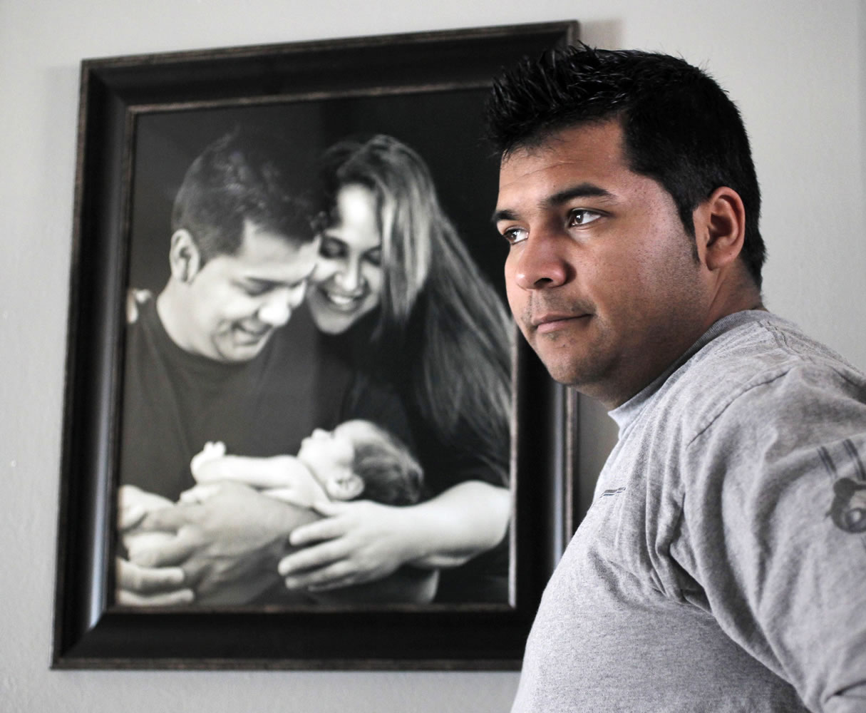 Erick Munoz stands Jan. 3 with a portrait of himself with his wife, Marlise, and their son Mateo in Haltom City, Texas. Marlise Munoz met the criteria to be declared dead almost two months ago, but the hospital where she was taken Nov. 26 has refused to do so.