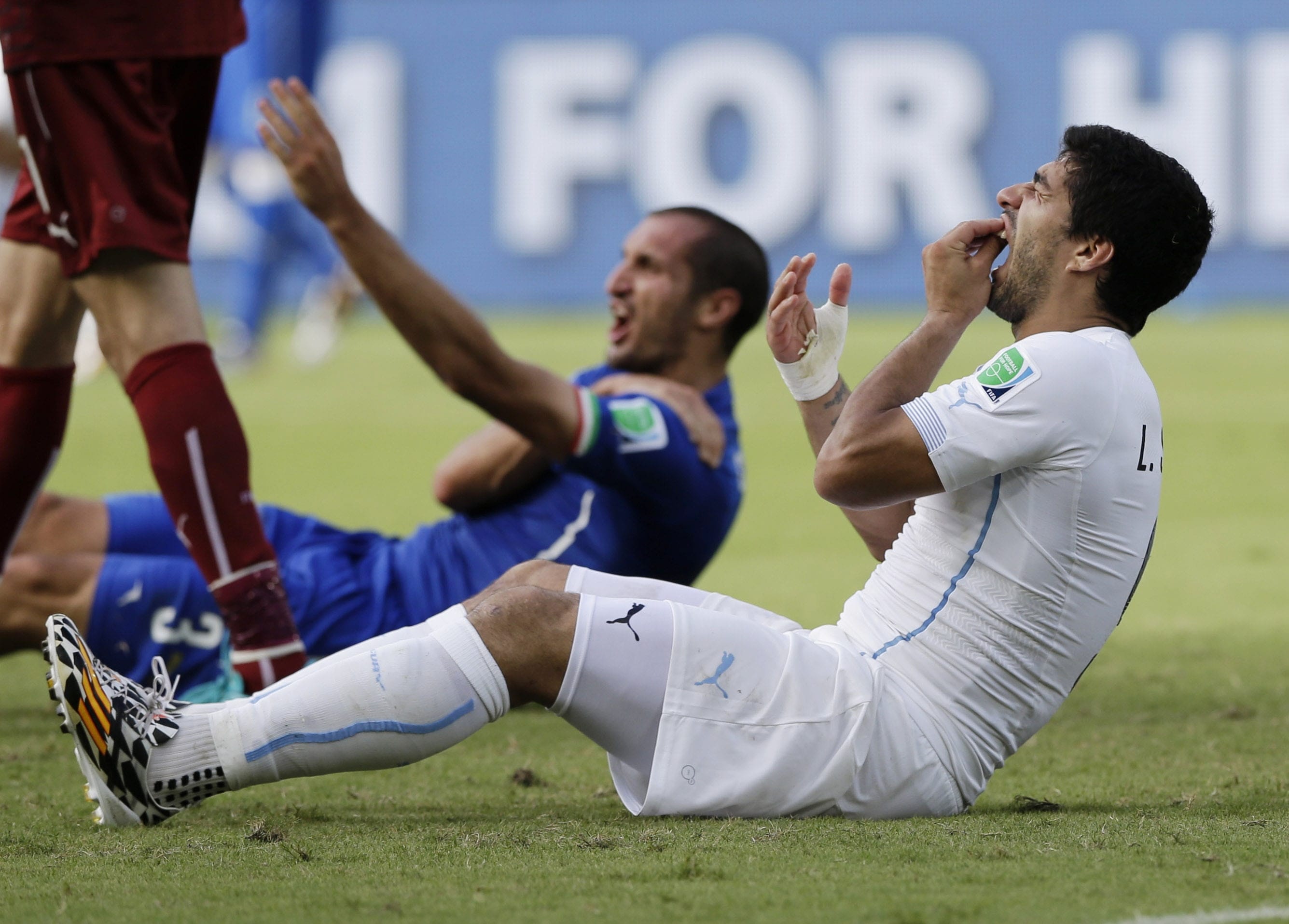 Uruguay's Luis Suarez holds his teeth after biting Italy's Giorgio Chiellini's shoulder during the group D World Cup soccer match between Italy and Uruguay at the Arena das Dunas in Natal, Brazil.