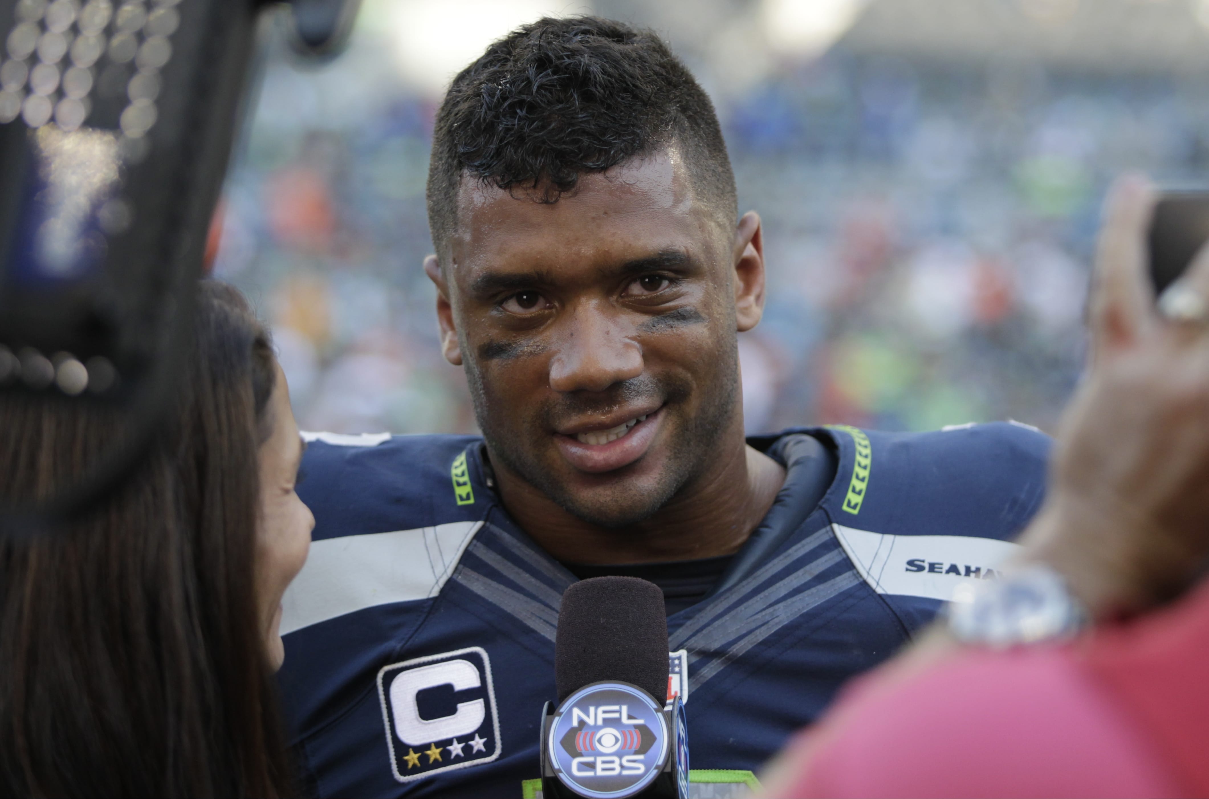 Seattle Seahawks quarterback Russell Wilson is interviewed on the field after defeating the Denver Broncos in overtime on Sunday, Sept. 21, 2014, in Seattle.