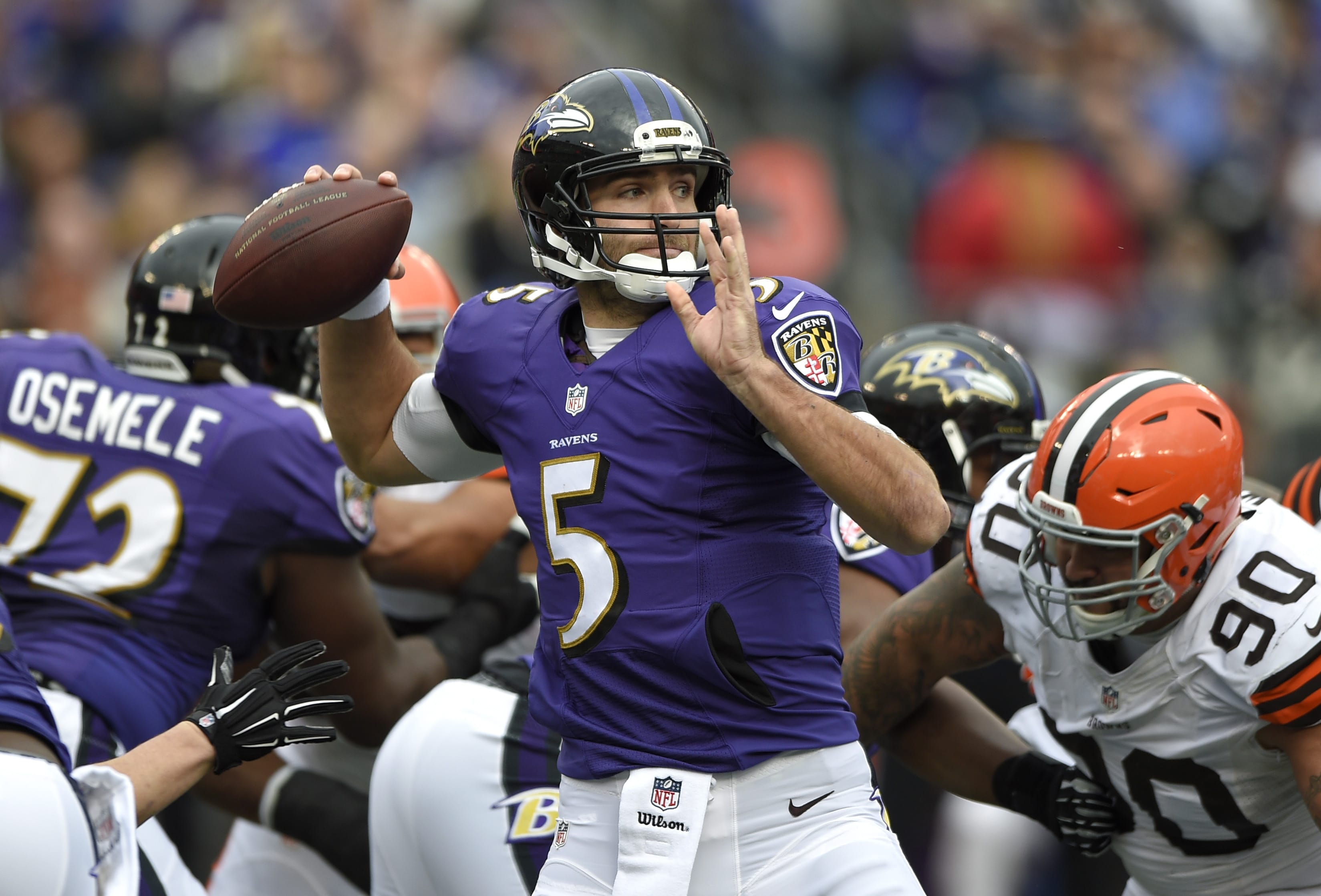 Baltimore Ravens quarterback Joe Flacco, center, throws to a receiver as he is pressured by Cleveland Browns defensive end Billy Winn (90) in the first half Sunday, Dec. 28, 2014, in Baltimore.
