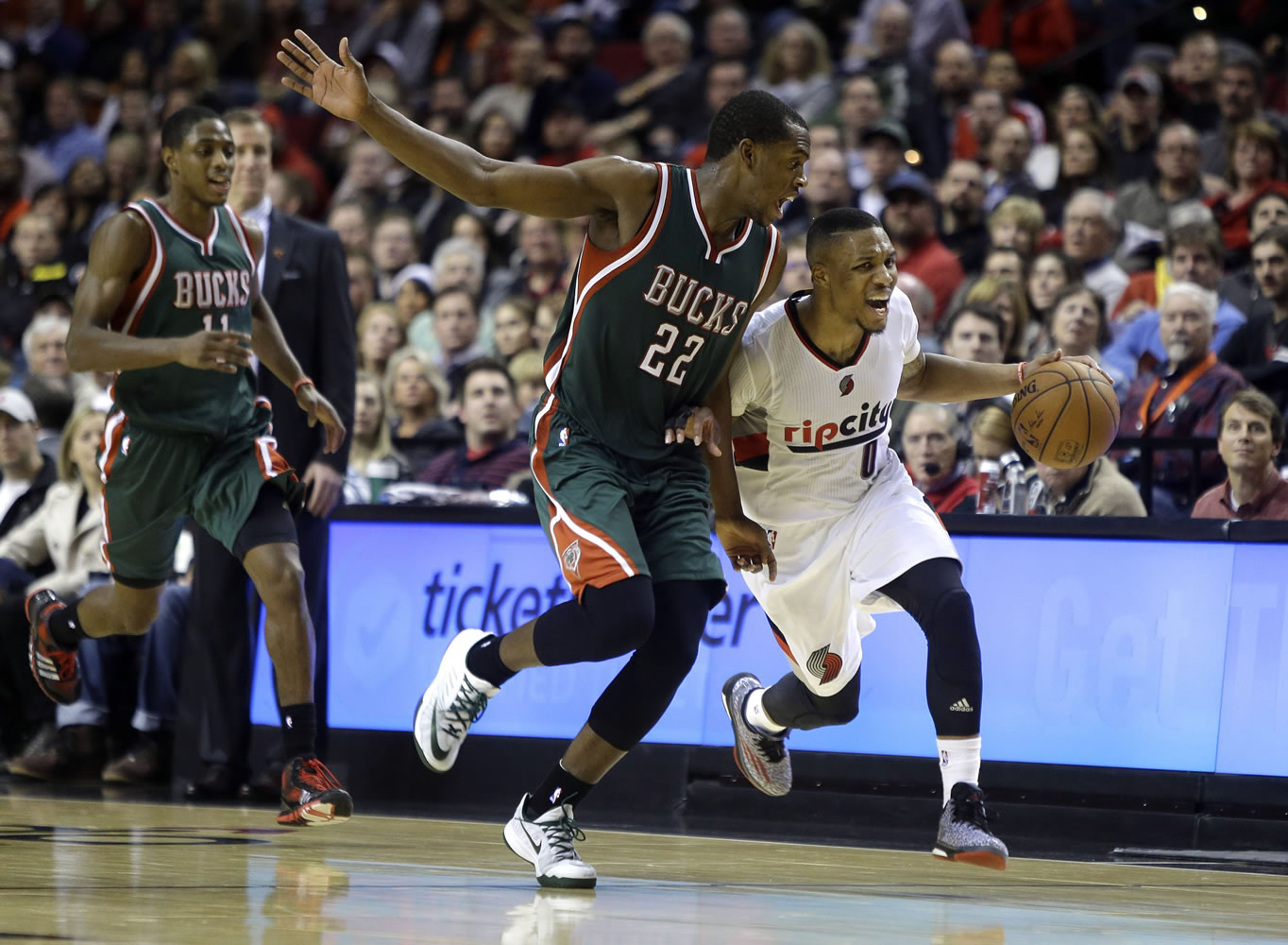 Portland Trail Blazers guard Damian Lillard, right, races downcourt against Milwaukee Bucks forward Khris Middleton during the second half of an NBA basketball game in Portland, Ore., Wednesday, Dec. 17, 2014. Lillard led the Trail Blazers in scoring with 29 points as they defeated the Bucks 104-97.