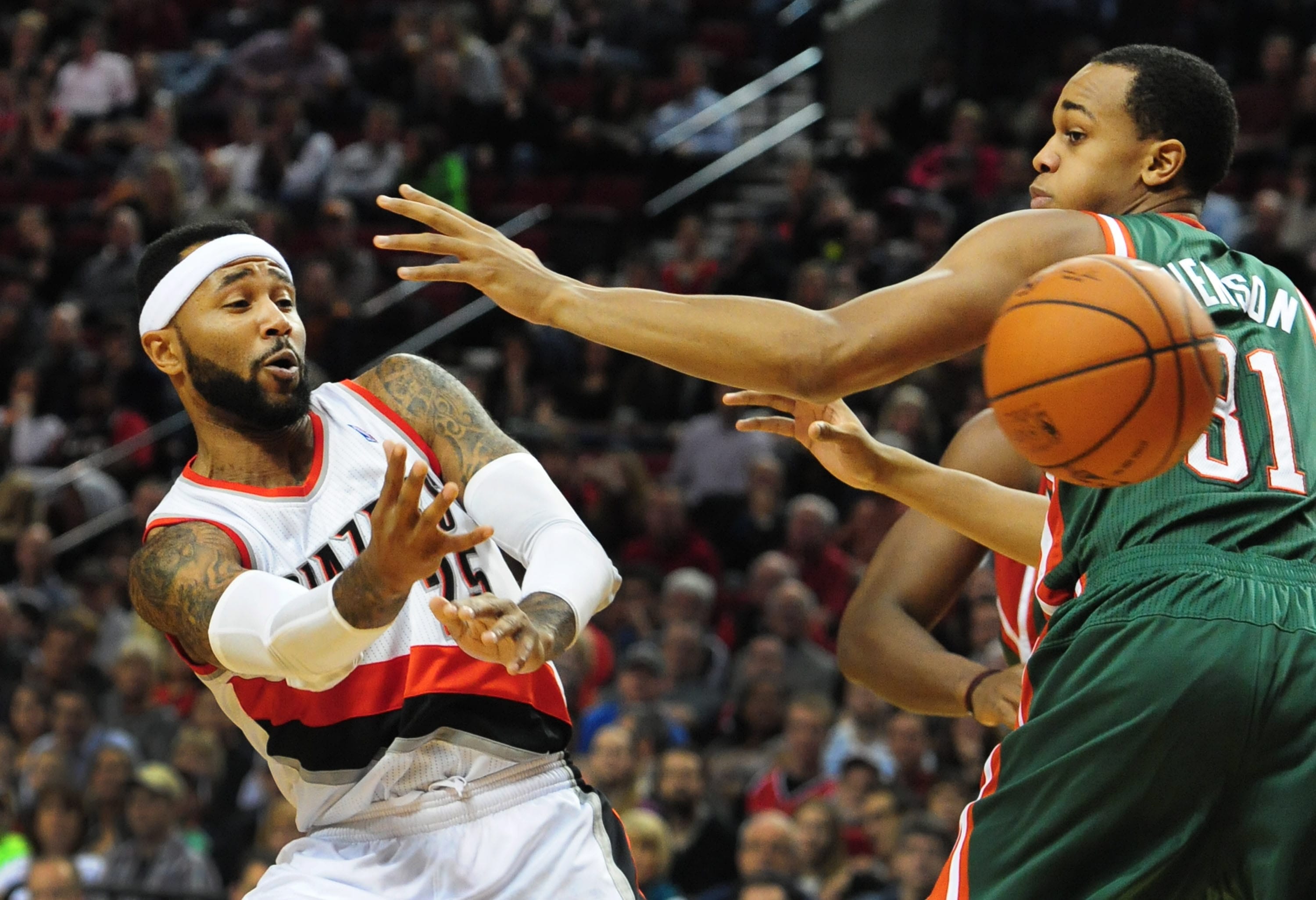 Portland Trail Blazers guard Mo Williams (25) passes the ball around Milwaukee Bucks center John Henson (31) during the second half of an NBA basketball game in Portland, Ore., Tuesday, March 18, 2014. The Blazers won the game 120-115 in overtime.
