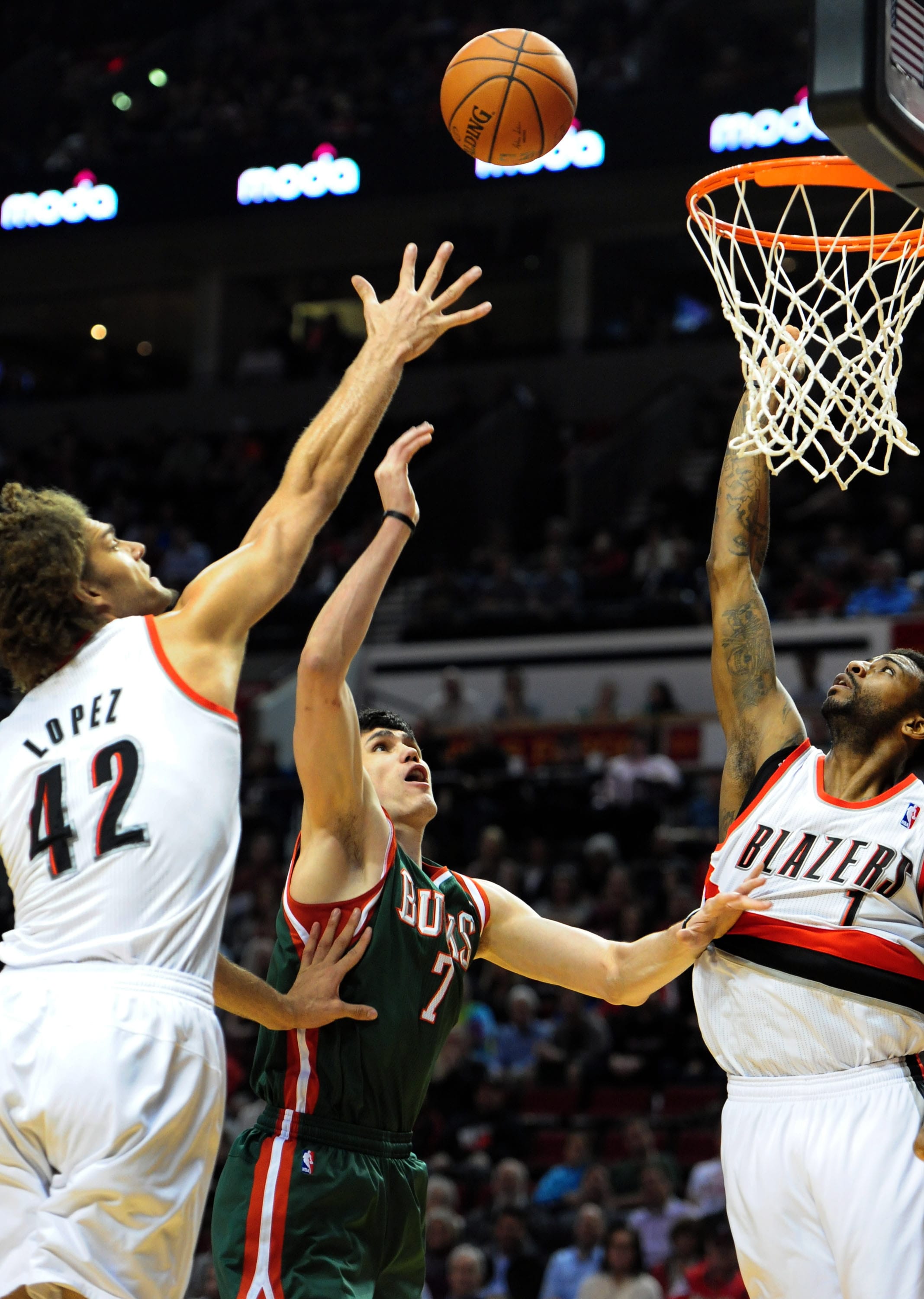 Milwaukee Bucks forward Ersan Ilyasova (7) drives to the basket on Portland Trail Blazers center Robin Lopez (42) and forward Dorell Wright (1) during the first half of an NBA basketball game in Portland, Ore., Tuesday, March 18, 2014.