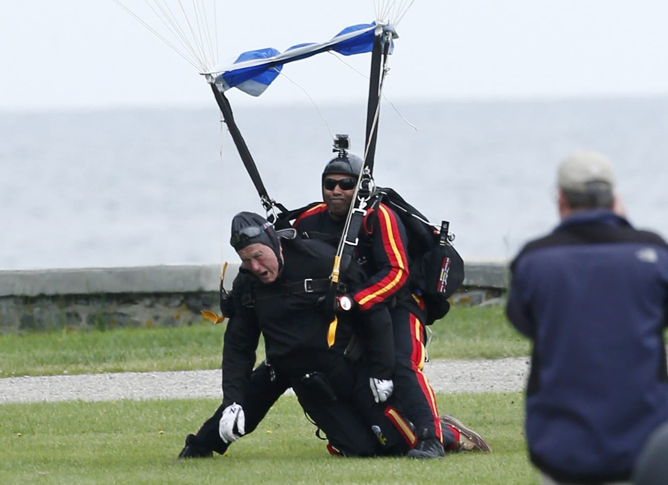 Former President George H.W. Bush, left, strapped to Sgt. 1st Class Mike Elliott, a retired member of the Army's Golden Knights parachute team, land on the lawn at St.