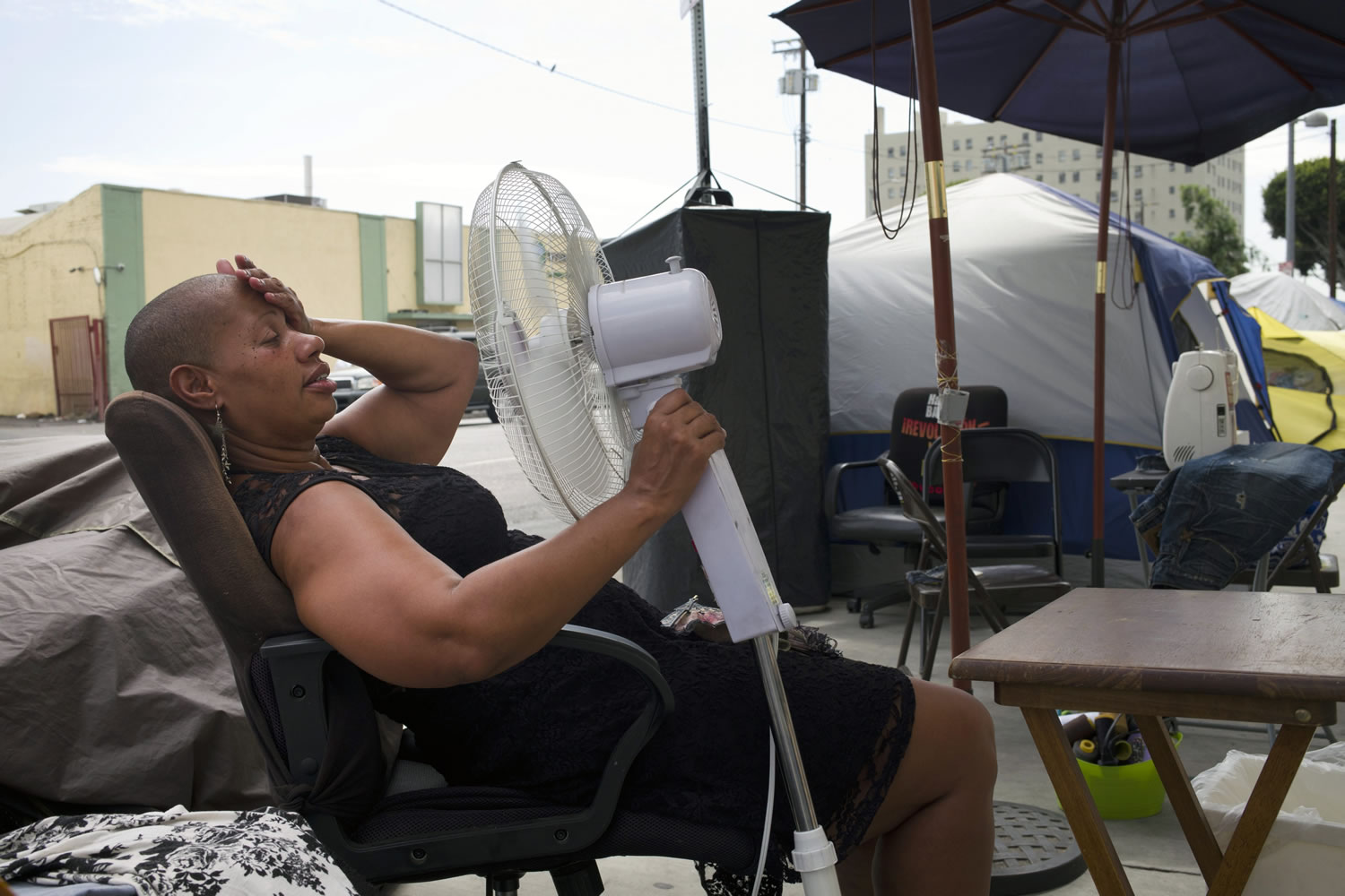 Stephanie Williams, 53, cools off using a fan running on a portable battery, Thursday, Sept. 10, 2015, in the Skid Row area of Los Angeles. Much of California simmered in a stew of high heat and humidity on Thursday, bracing for more thunderstorms and flash floods that have already killed one person and left scattered damage and power outages. (AP Photo/Jae C.