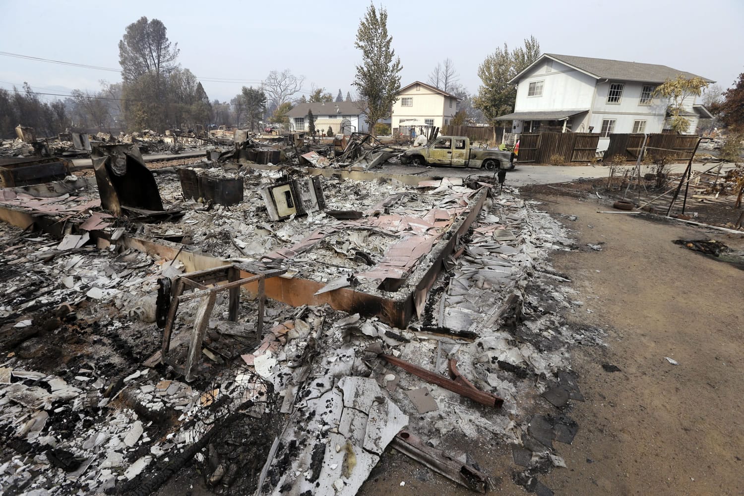 Houses remain standing and with little damage in view of others that were destroyed in a wildfire several days earlier, Tuesday, Sept. 15, 2015, in Middletown, Calif. The fire that sped through Middletown and other parts of rural Lake County, less than 100 miles north of San Francisco, has continued to burn since Saturday despite a massive firefighting effort.