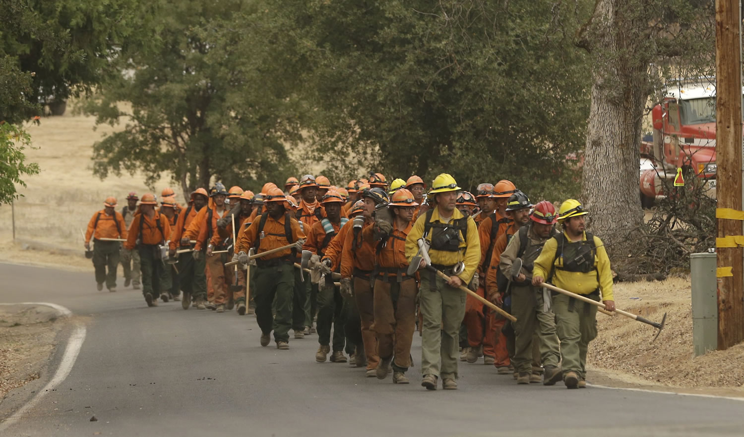 A California Department of Corrections and Rehabilitation inmate work crew walks through Sheep Ranch, Calif., on the way to battle a fire Sunday. Two of California's fastest-burning wildfires in decades overtook several Northern California towns, destroying homes and sending residents fleeing.