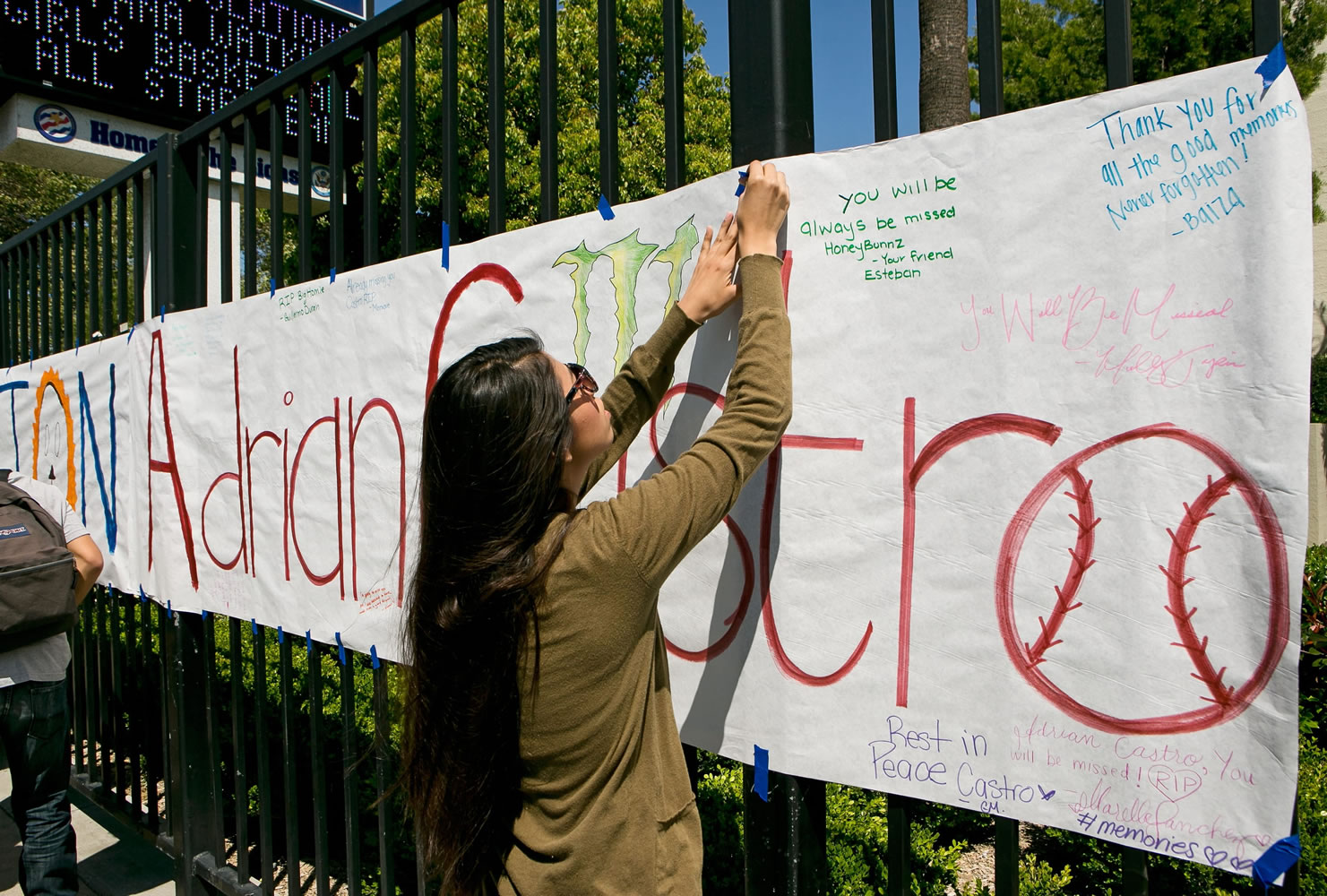 An El Monte High School student hangs a banner for senior Adrian Castro, outside El Monte High School in El Monte, Calif., Friday. Castro was killed when the Humboldt State University-bound bus he was on crashed in Orland on Thursday, an El Monte school official said.