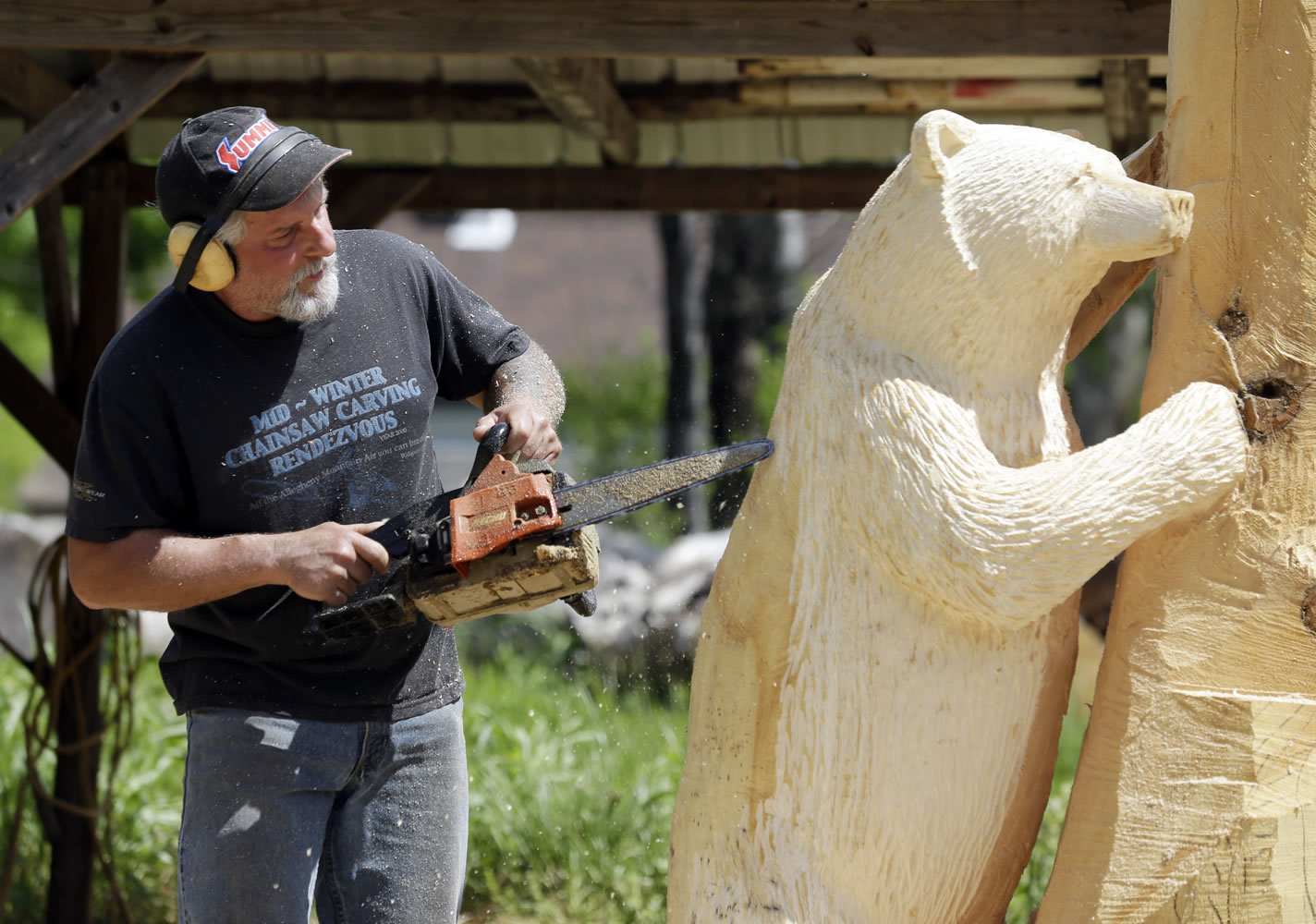 Mark Tyoe uses a chainsaw as he carves a bear sculpture from white pine May 29 in Salisbury, N.Y.